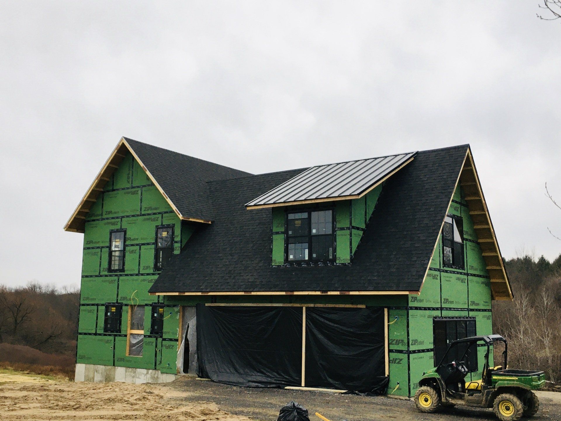 A john deere gator is parked in front of a house under construction.