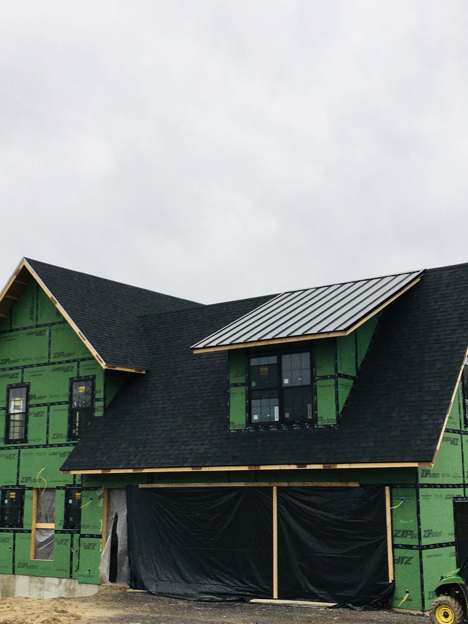 A house under construction with green siding and a black roof