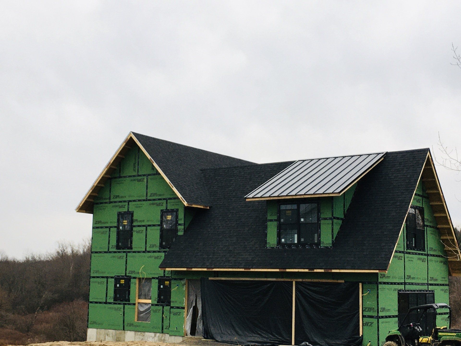 A house under construction with green siding and a black roof
