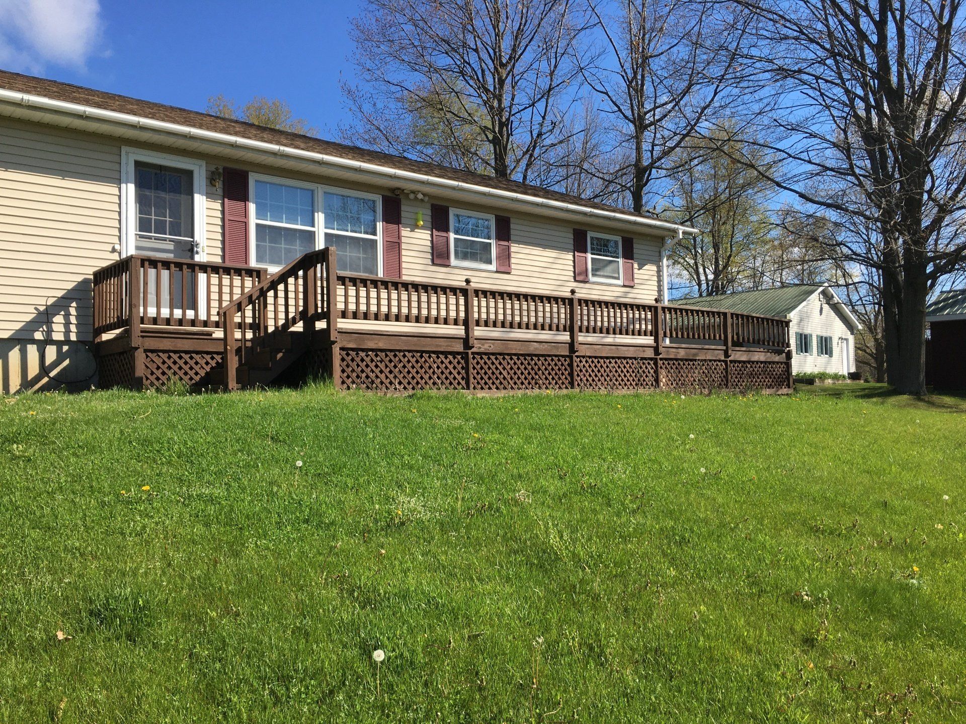 A mobile home with a large deck and stairs in the backyard.