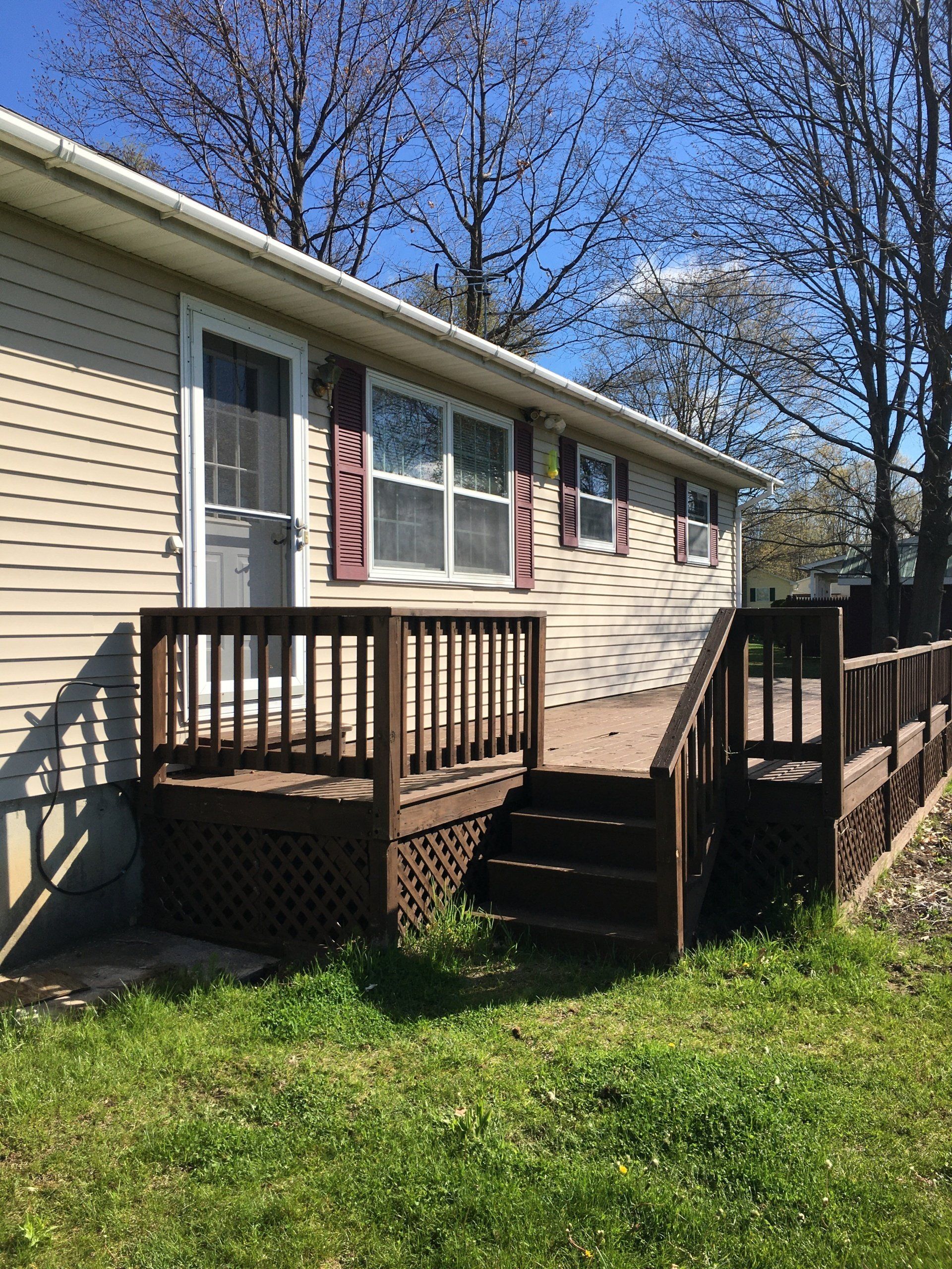 A mobile home with a deck and stairs in front of it.