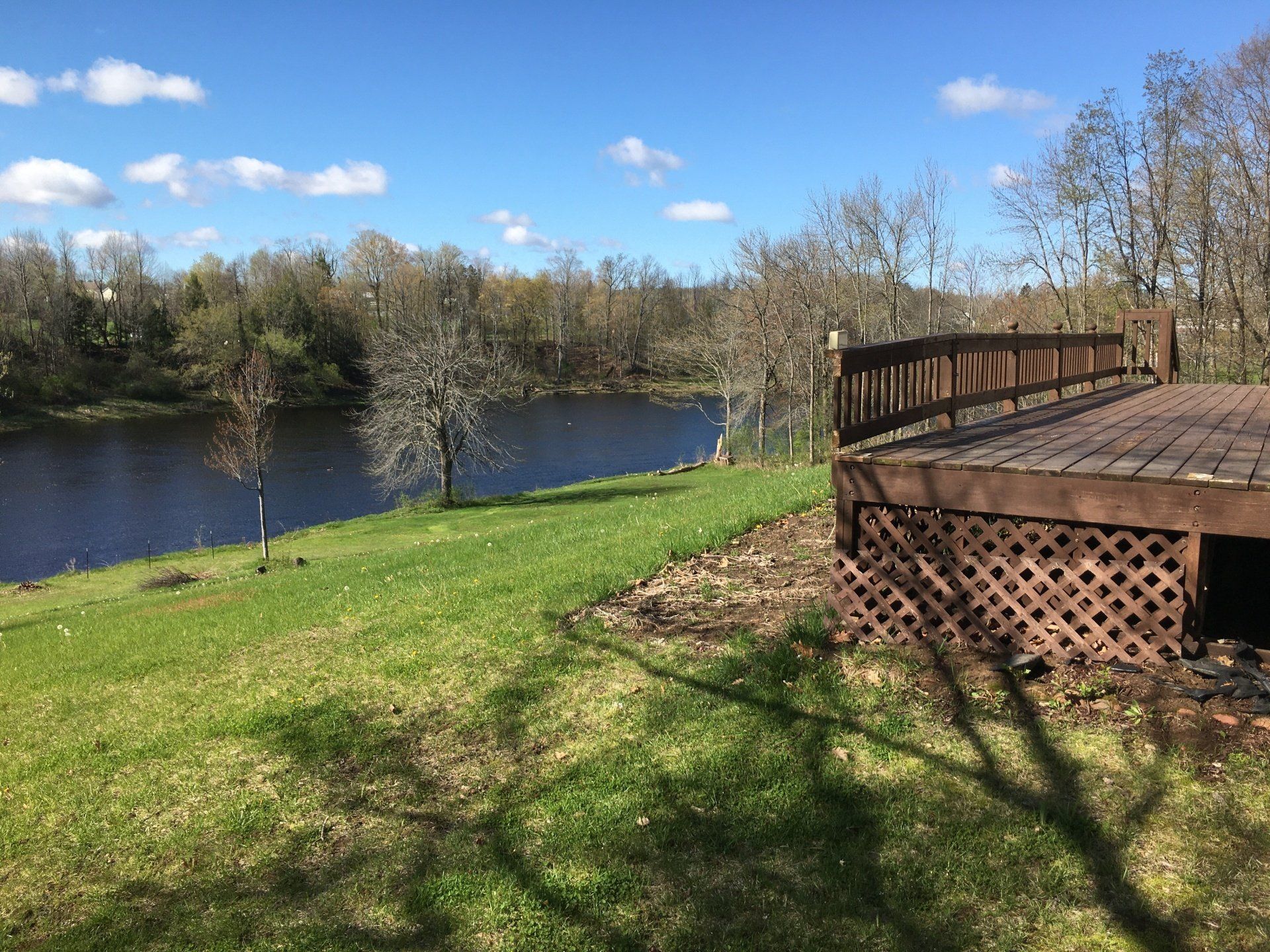A wooden deck overlooking a river with trees in the background
