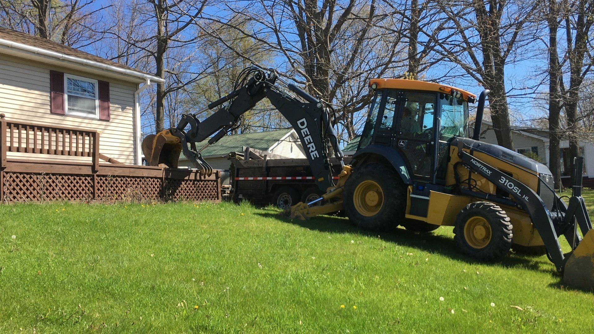 A yellow and black tractor is parked in front of a house.