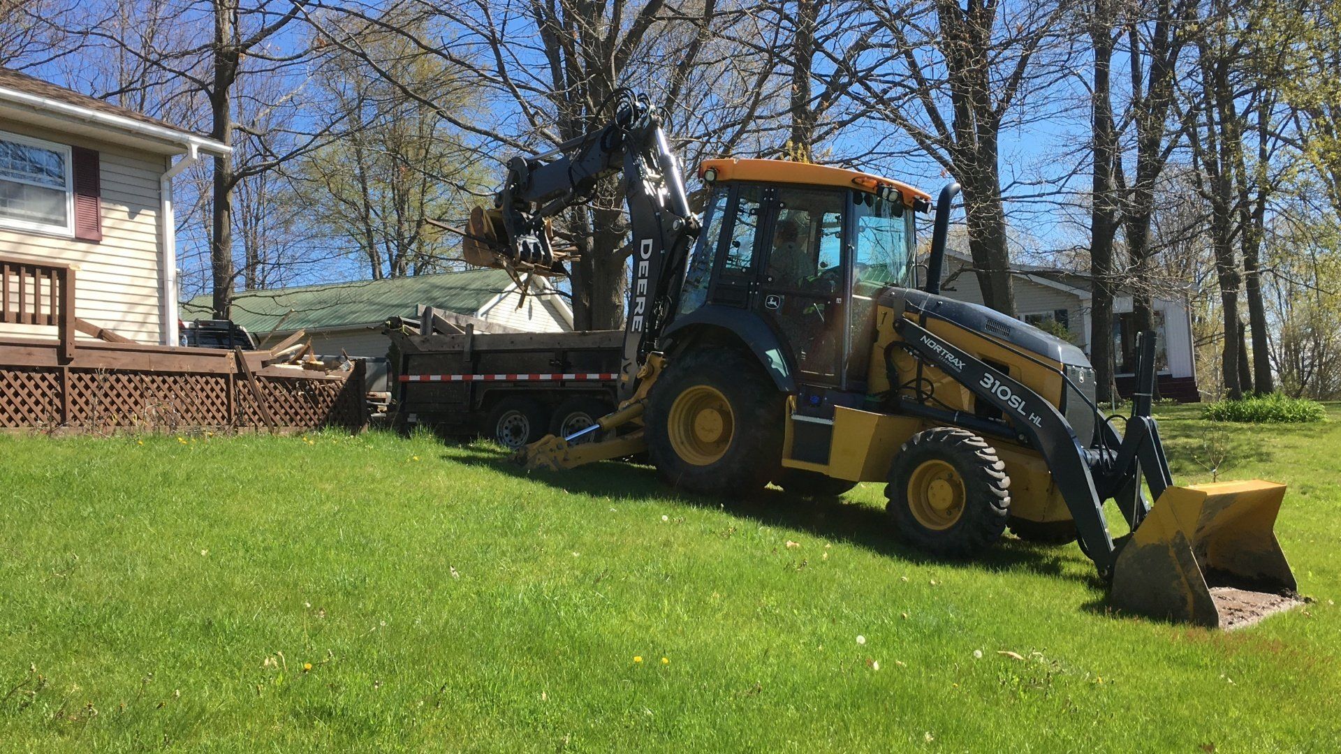 A yellow tractor is parked in a grassy yard next to a house.