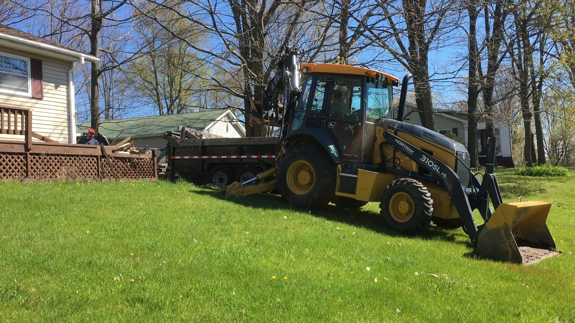 A tractor is parked in the grass in front of a house.
