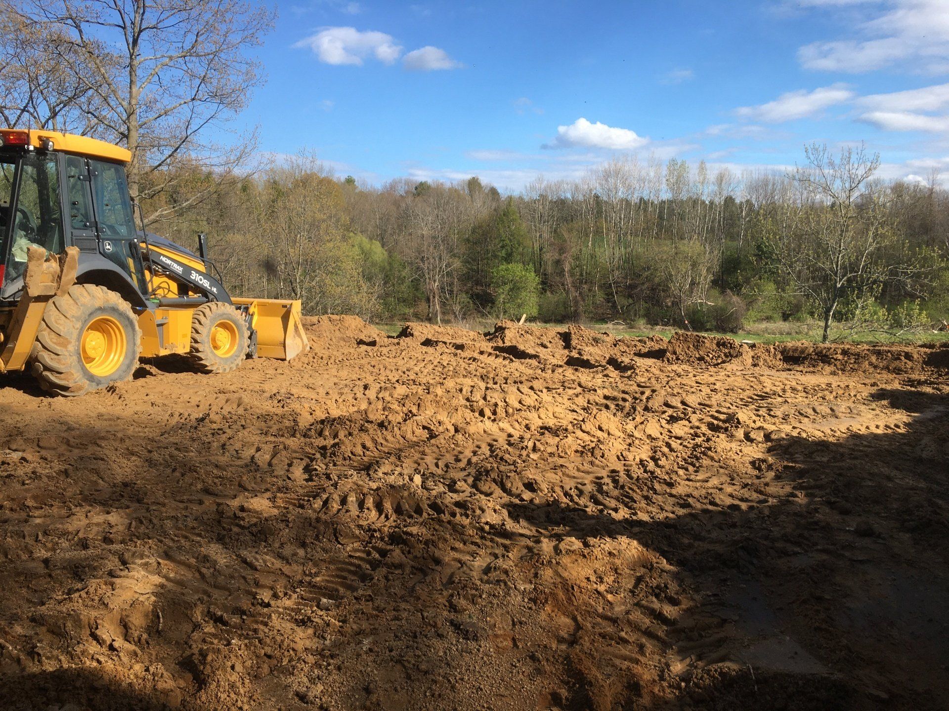 A yellow tractor is driving through a dirt field.