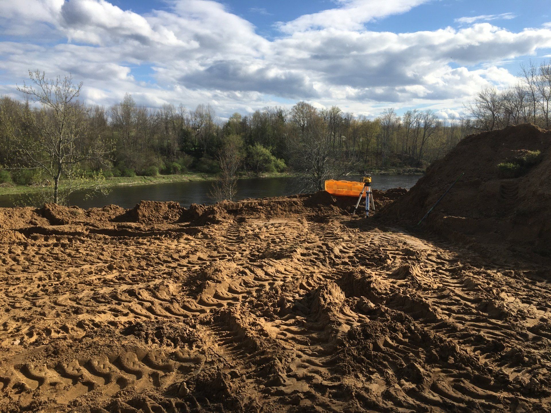 A large pile of dirt is sitting next to a body of water