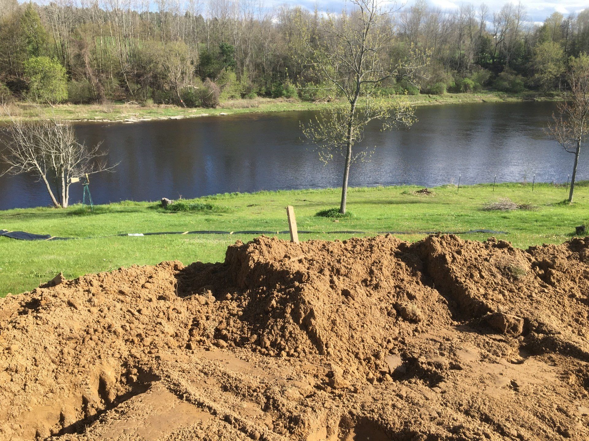A large pile of dirt is in front of a lake.