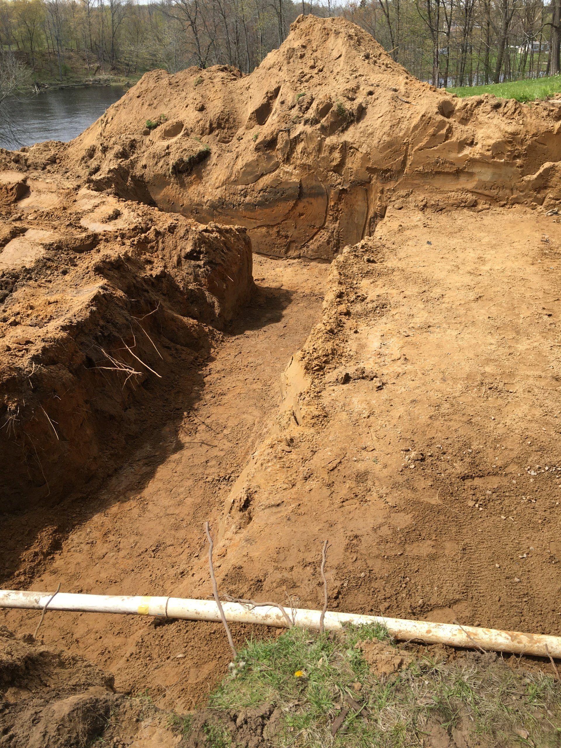 A pile of dirt is sitting next to a white pipe.