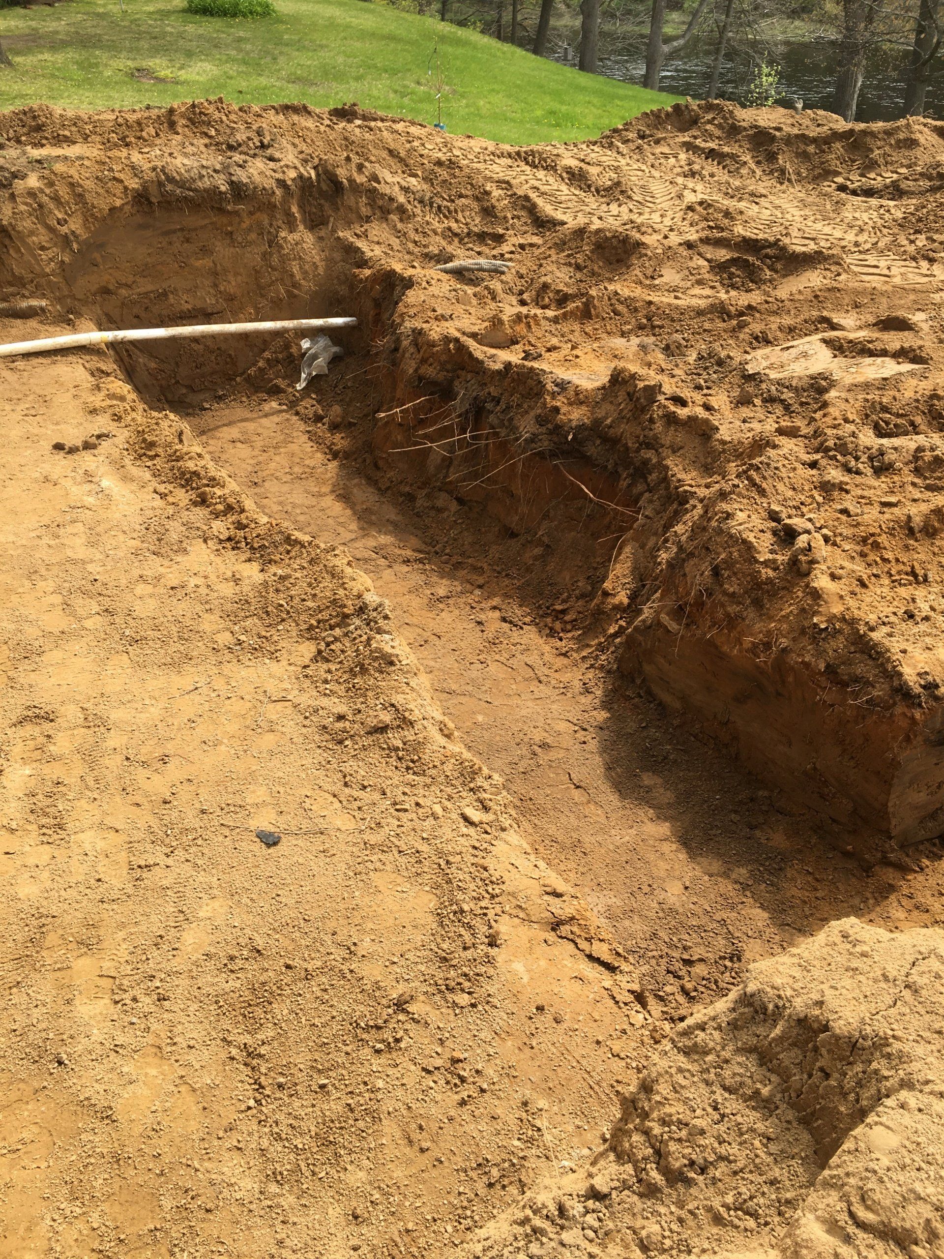 A large pile of dirt with a pipe sticking out of it.