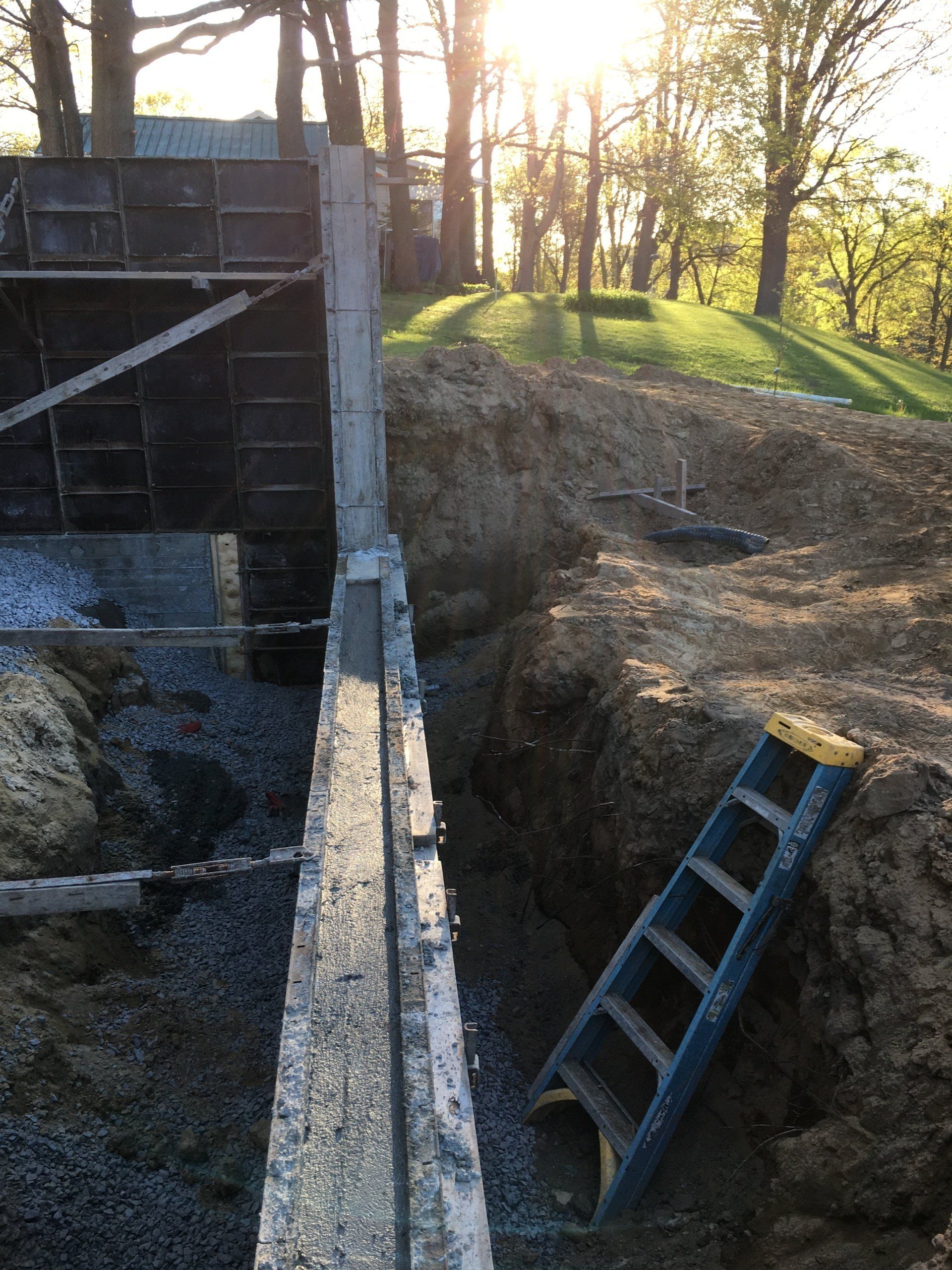 A ladder is laying in the dirt next to a wall.