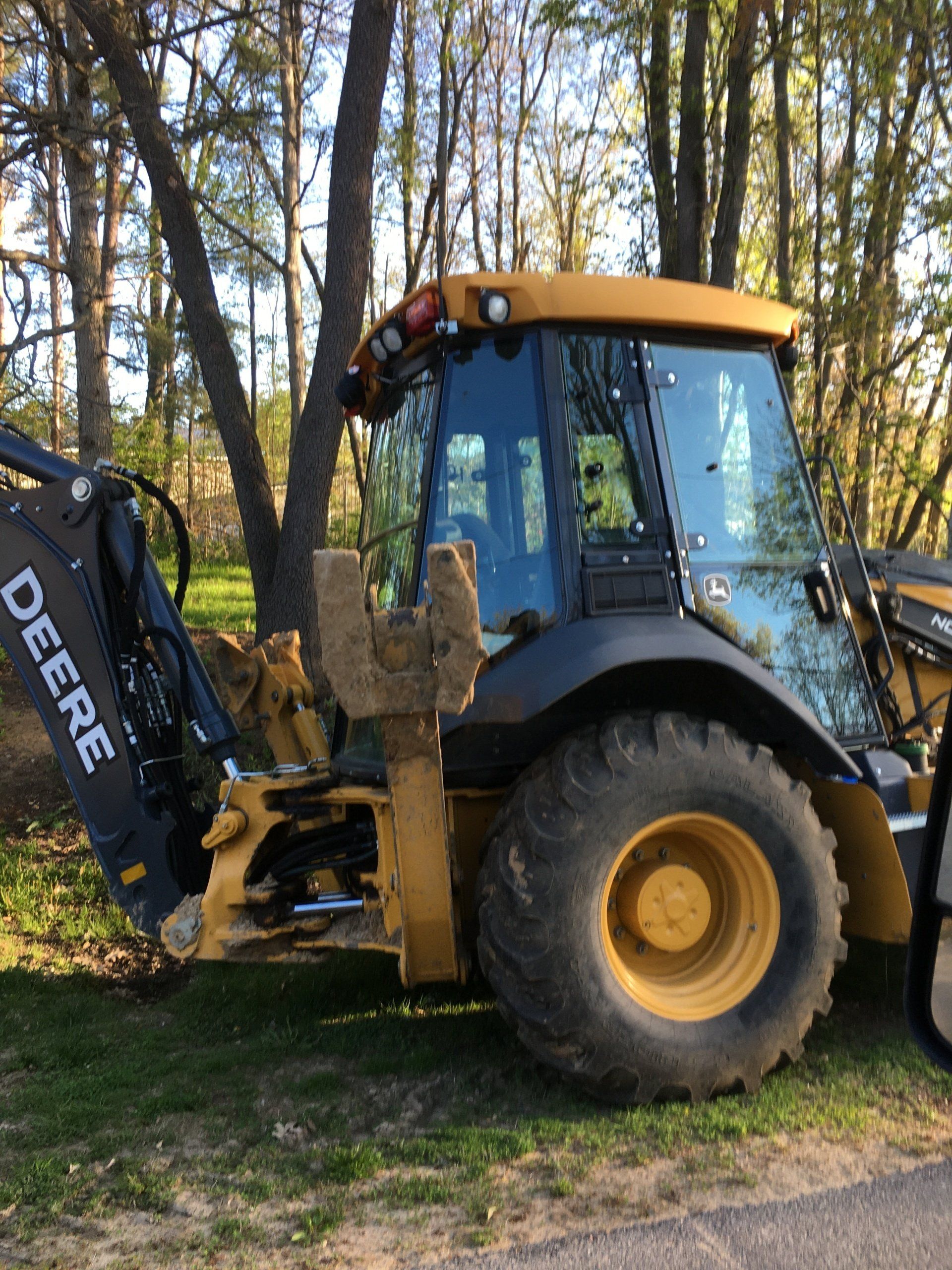 A yellow and black deere tractor is parked in the grass