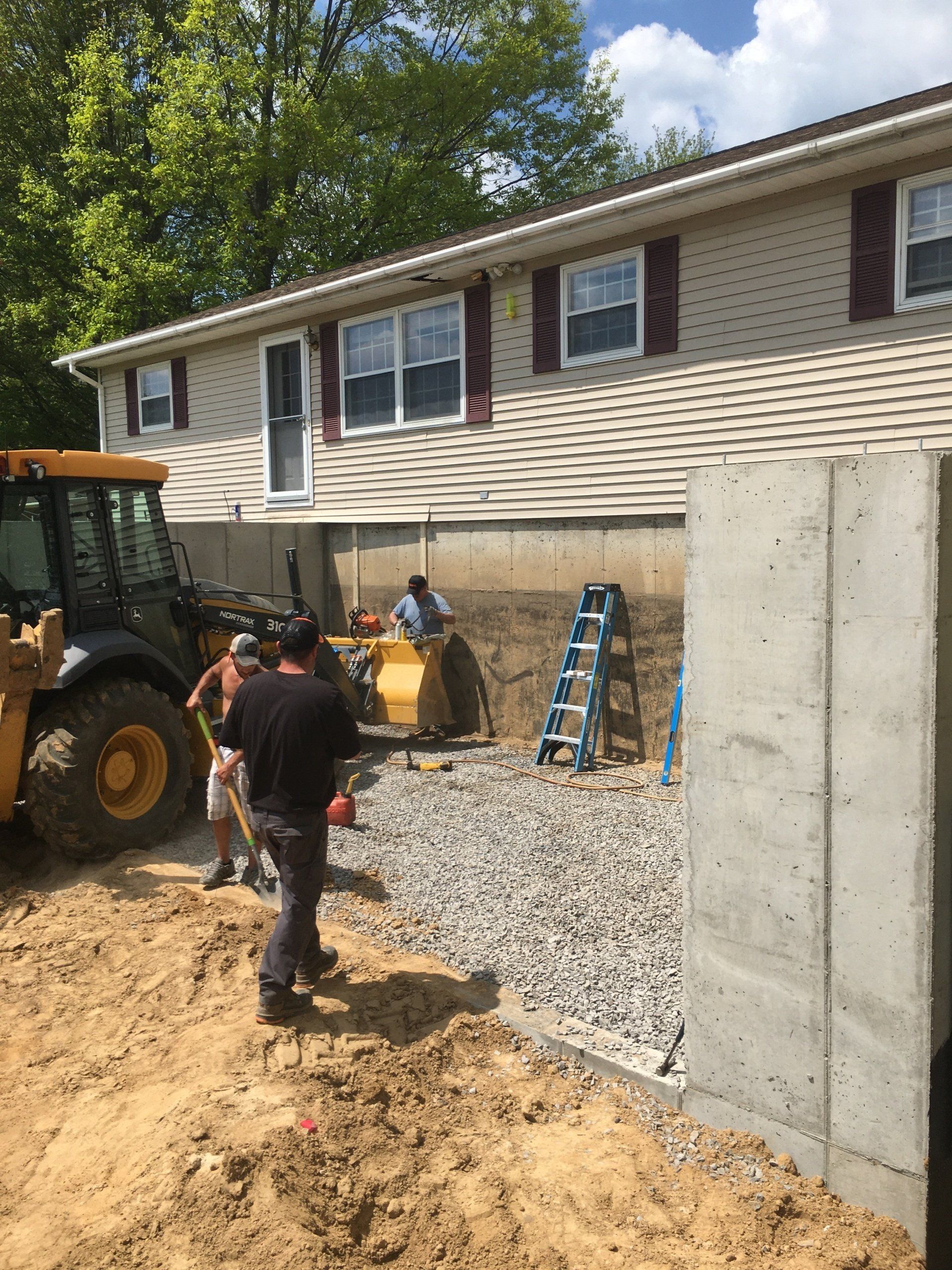 A man is standing in front of a house with a tractor in the background.