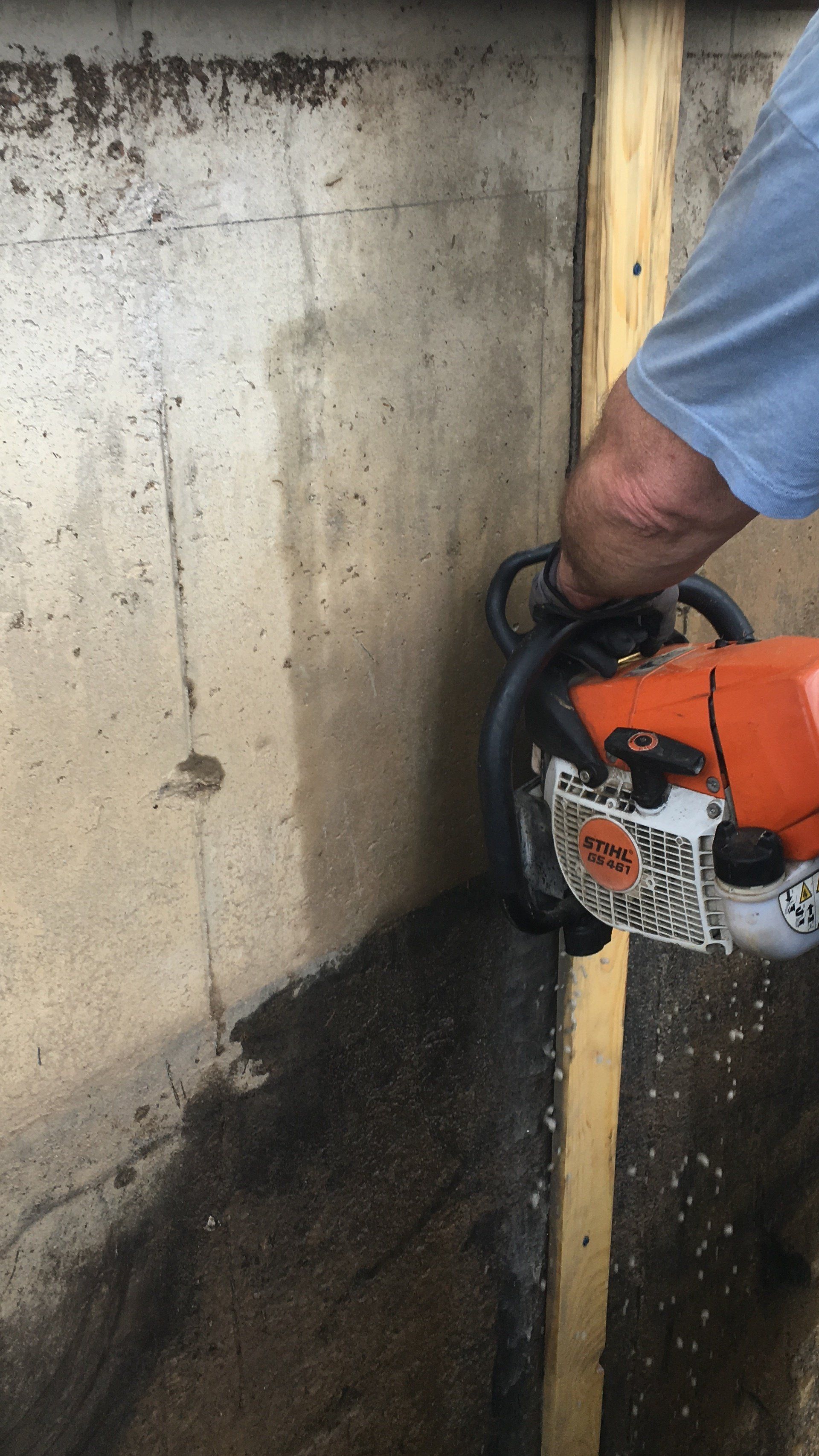 A man is cutting a piece of wood with a chainsaw.