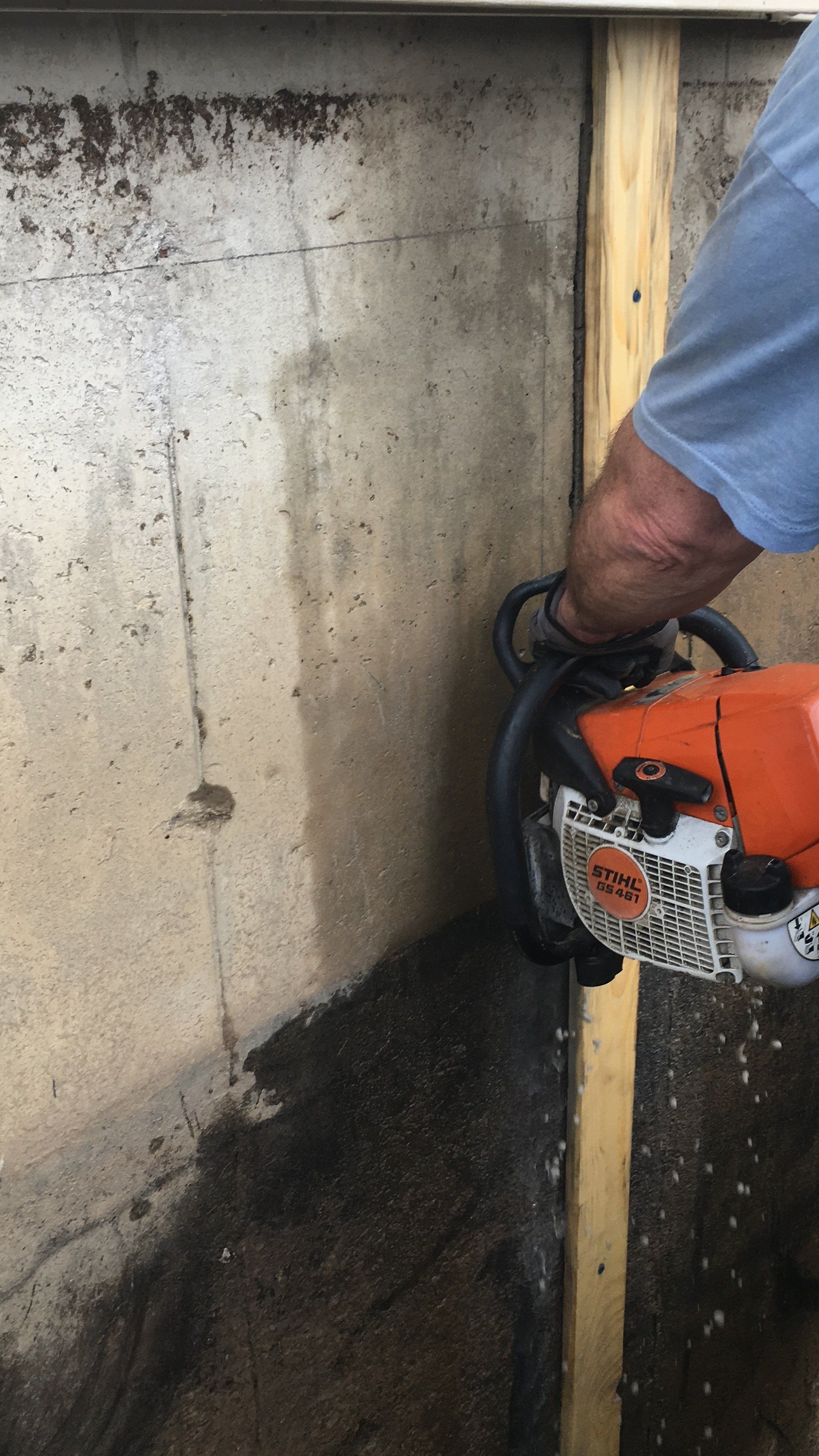 A man is using a chainsaw to cut a hole in a concrete wall.