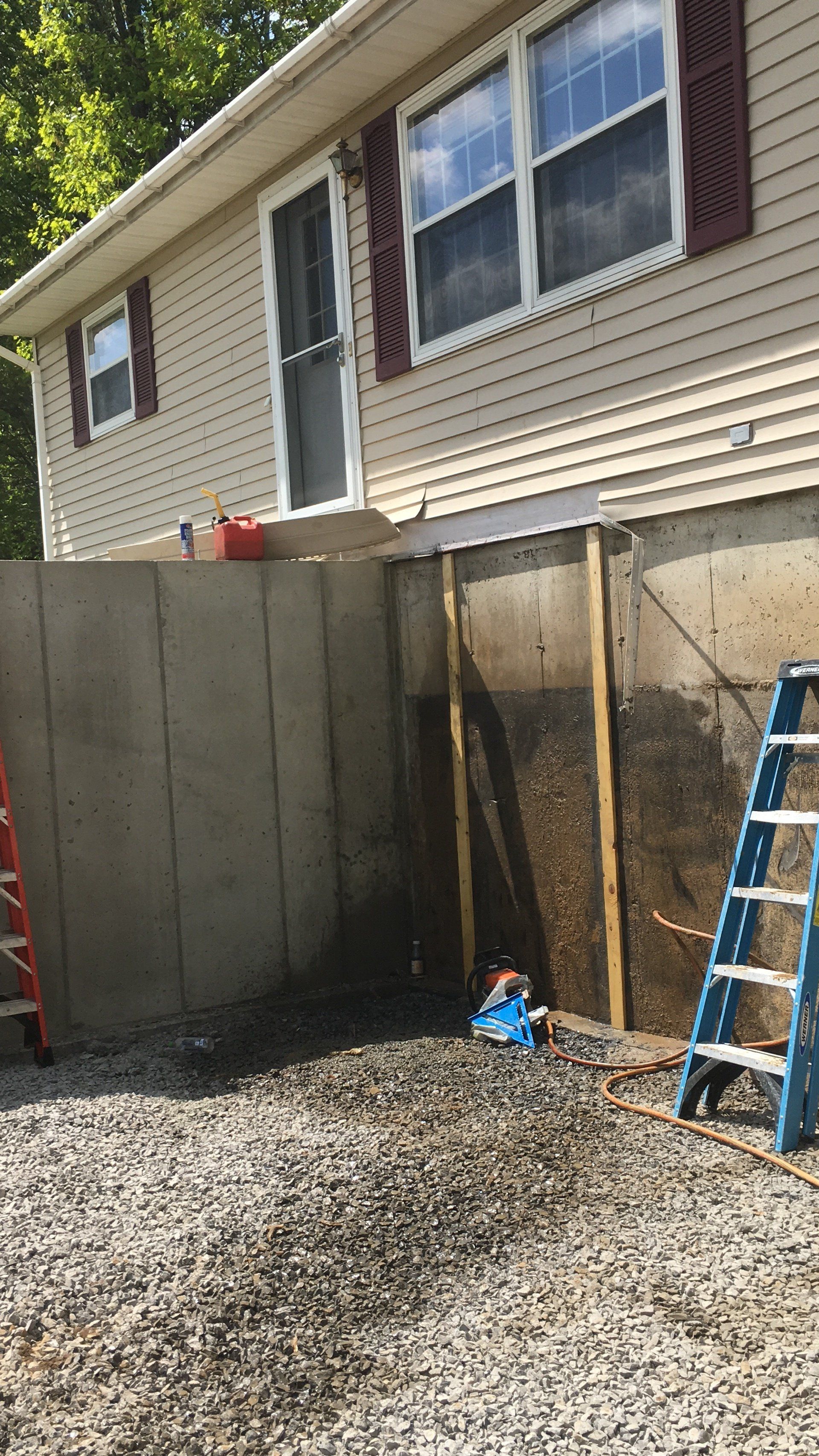 A concrete wall is being built in front of a house.