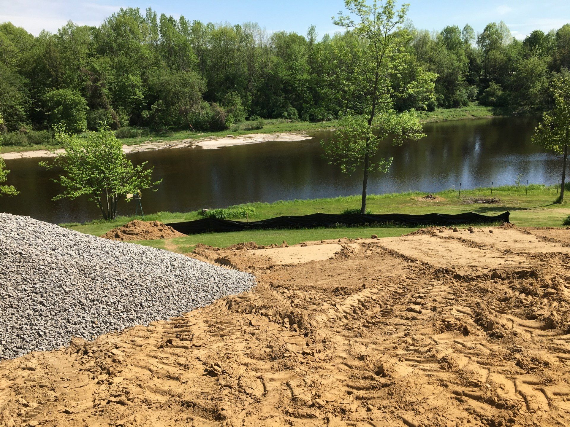 A large body of water is surrounded by trees and dirt.