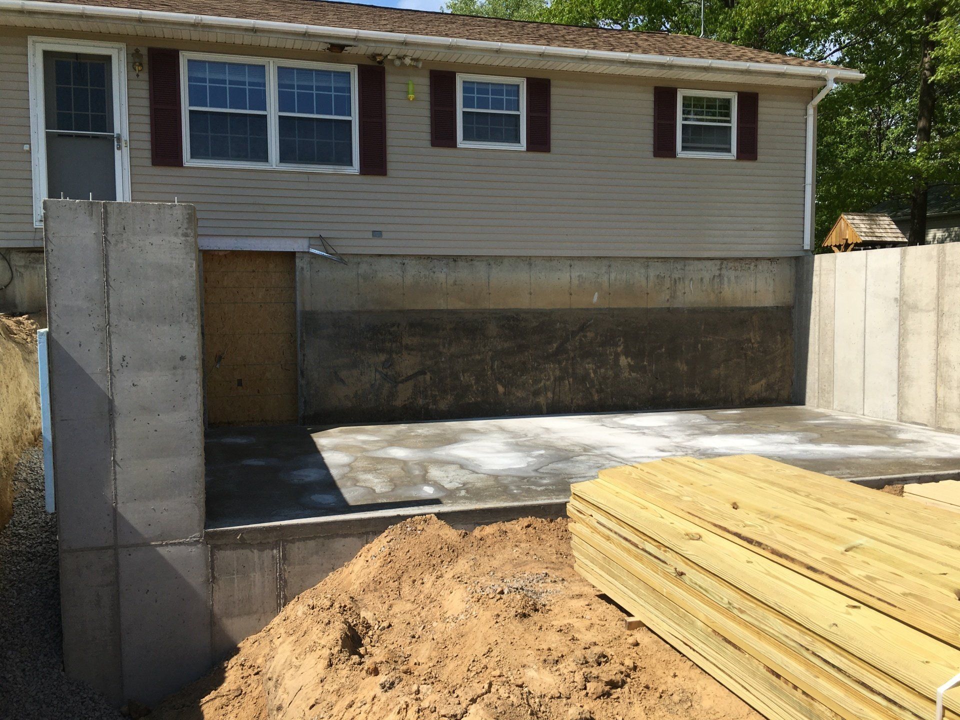 A house is being remodeled and a pile of wood is in front of it.
