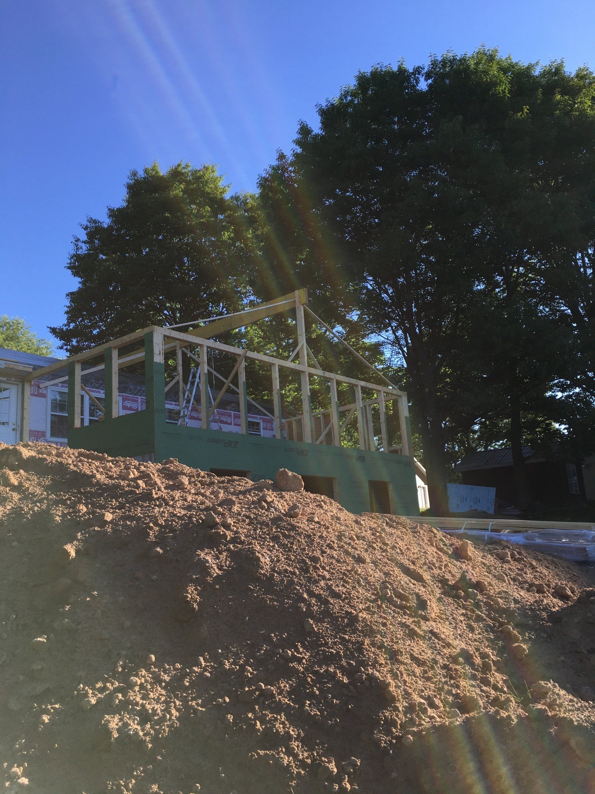 A house is being built on a hill with trees in the background