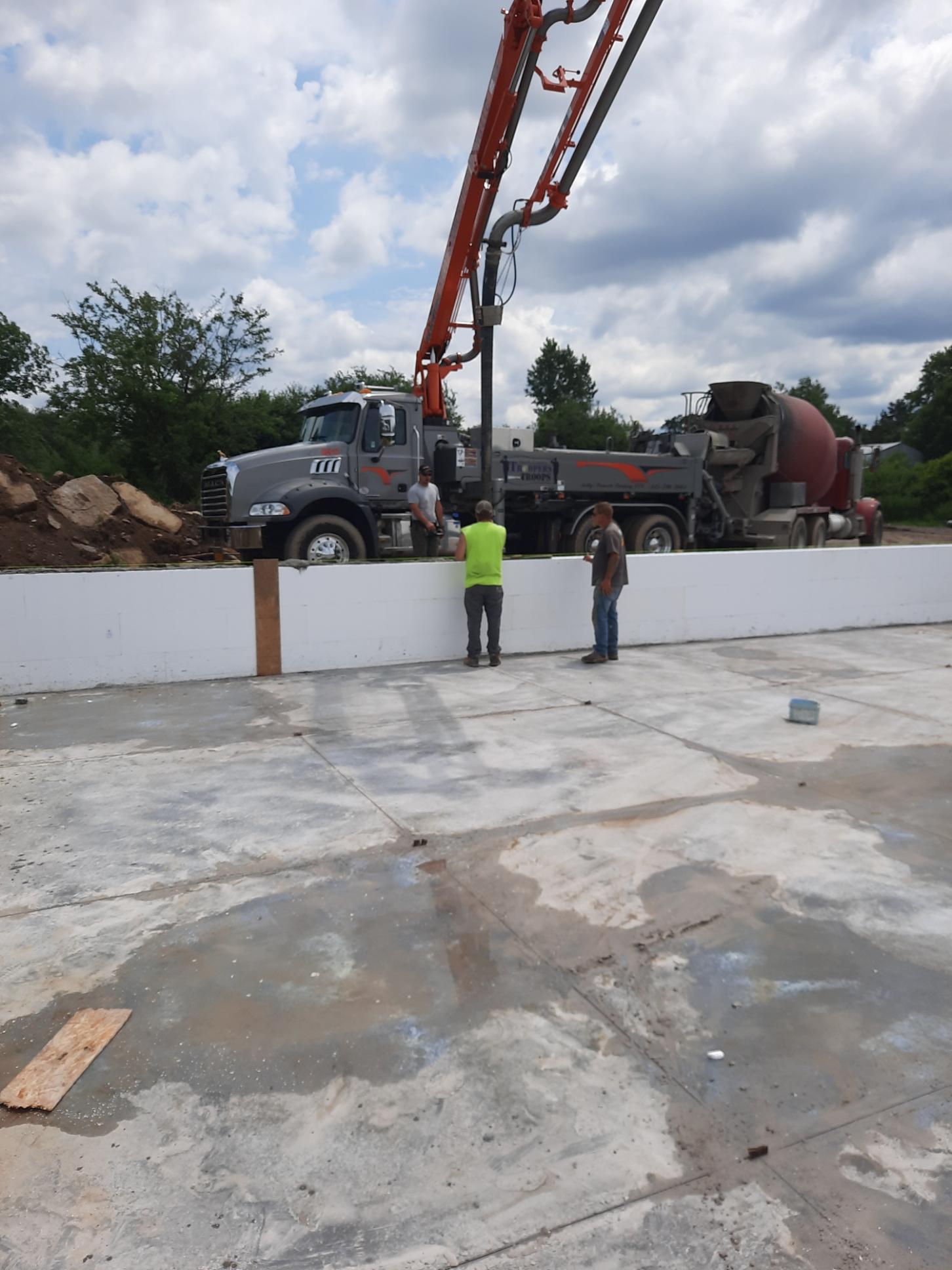A concrete pump is being used to pour concrete into a concrete wall