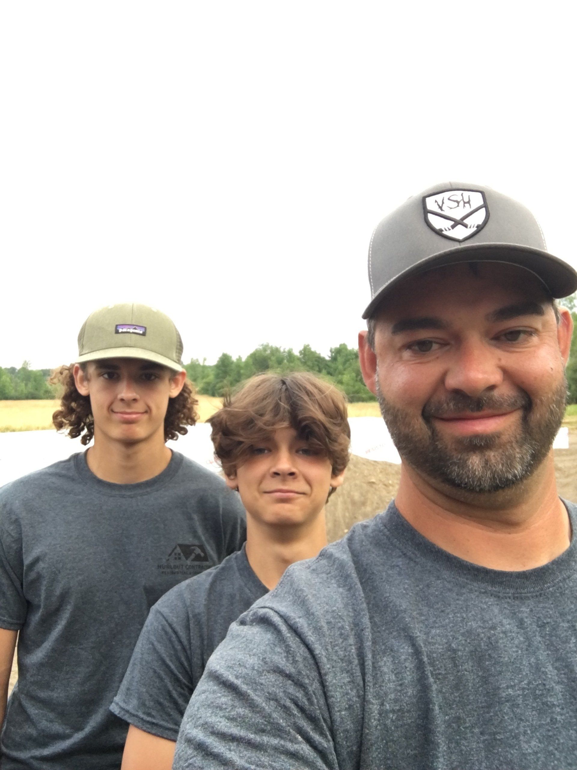 Three men are posing for a picture and one of them is wearing a patagonia hat