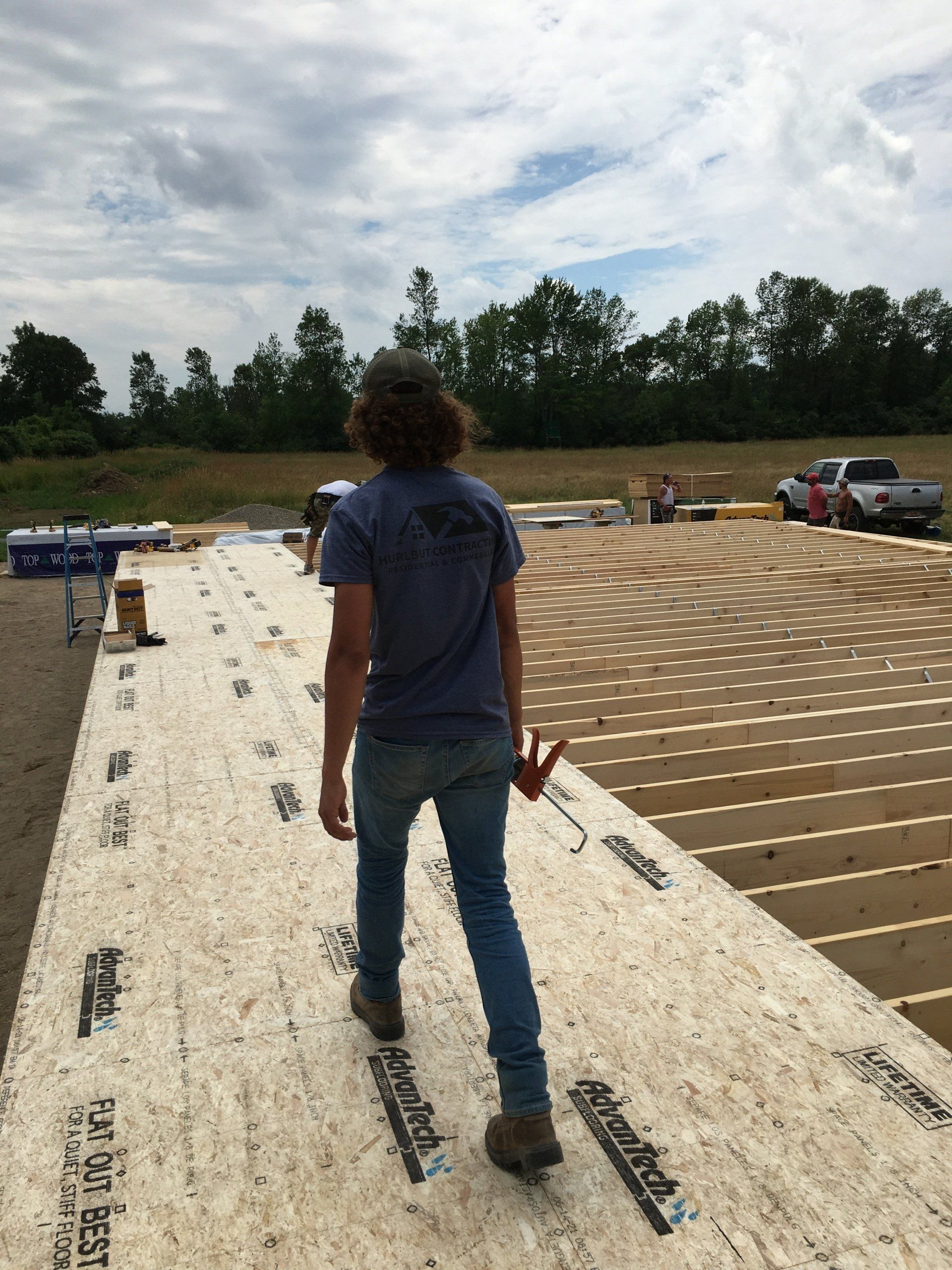 A man in a blue shirt is standing on a large piece of plywood