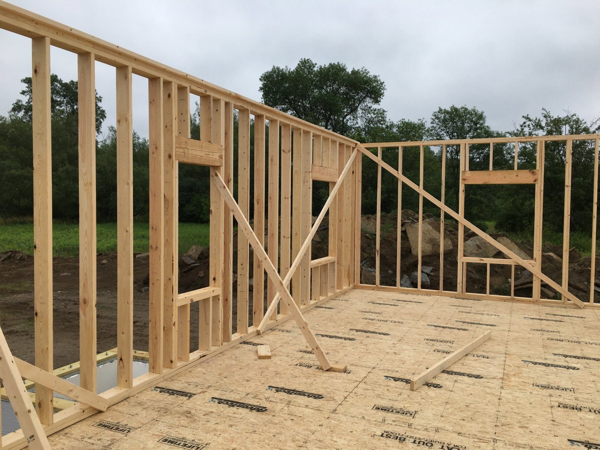 A wooden structure is being built in a field with trees in the background.