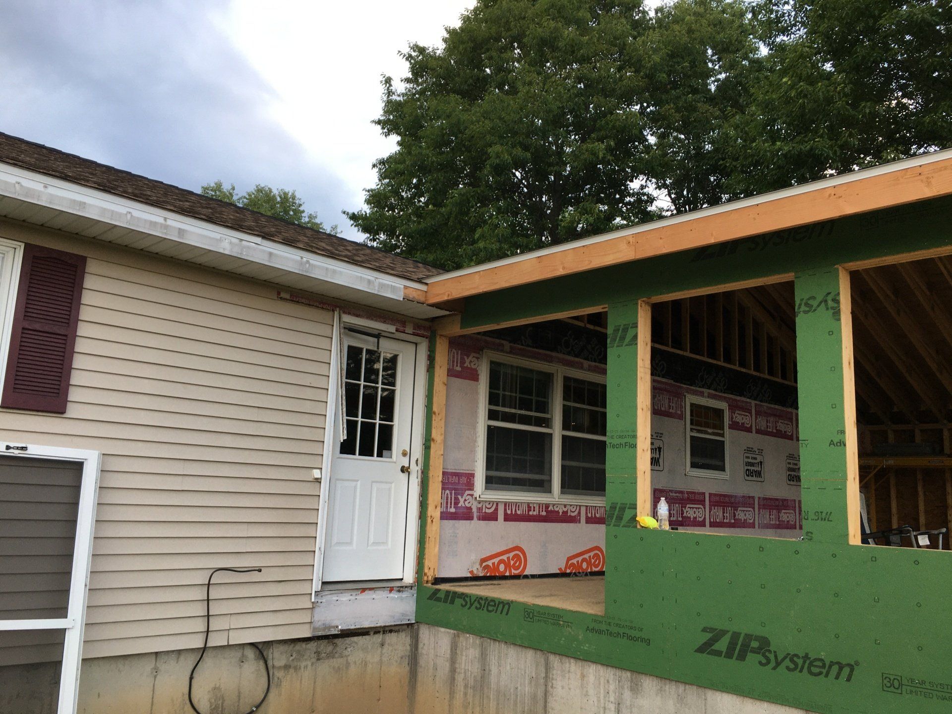 A house is being remodeled with a porch and a screen door.