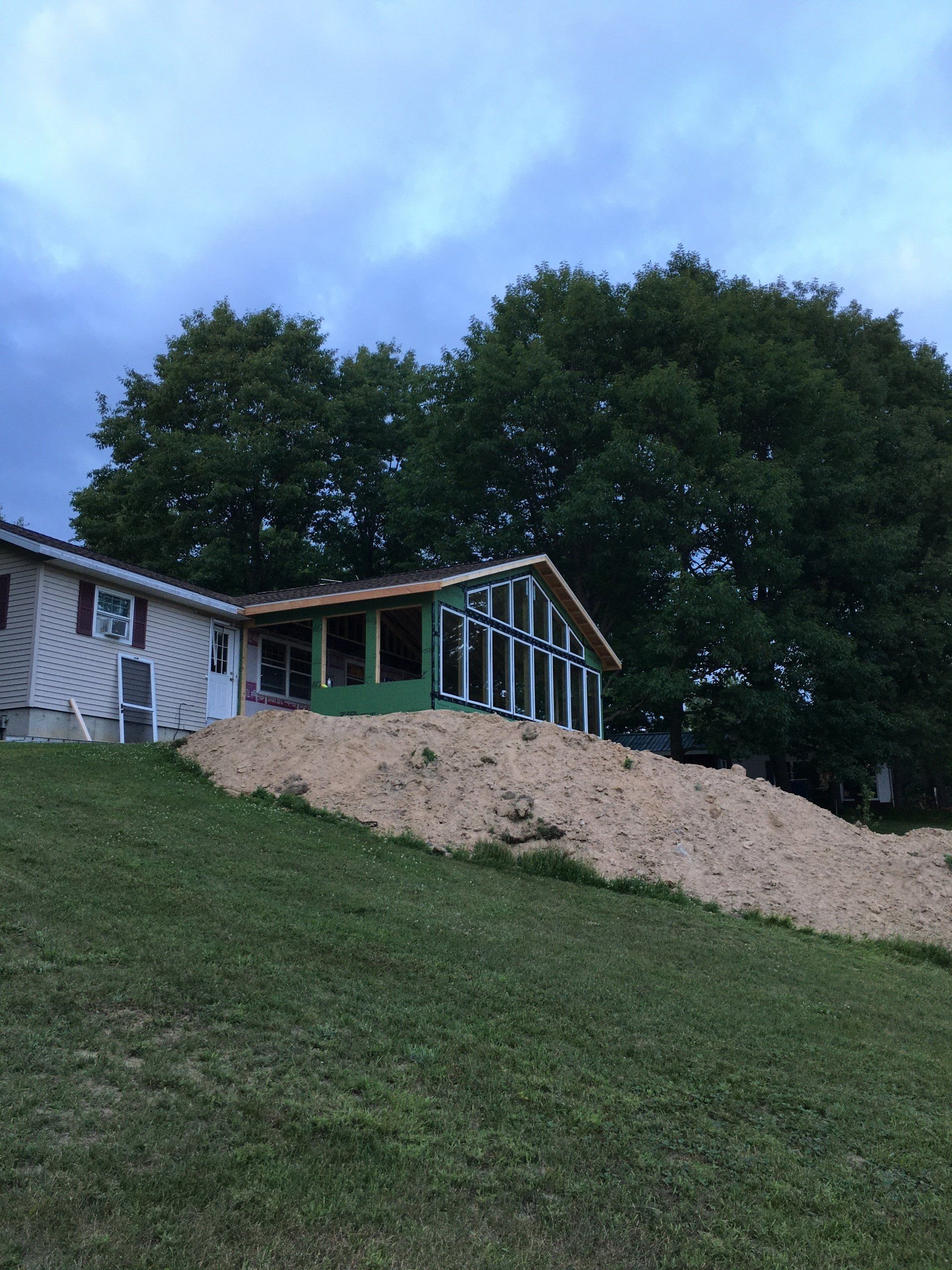 A house is being built on a hill with trees in the background.