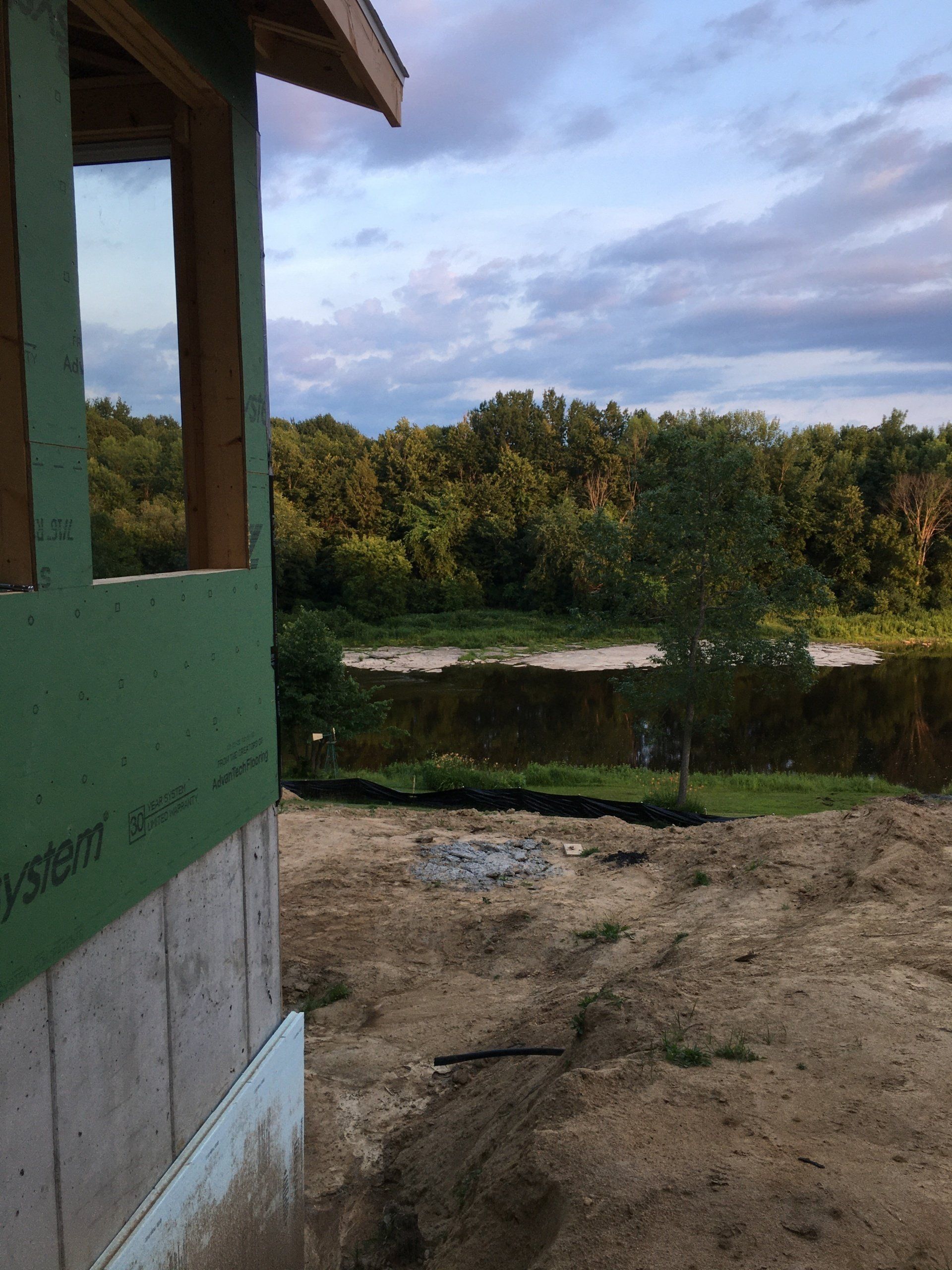 A house is being built in the middle of a field with trees in the background.