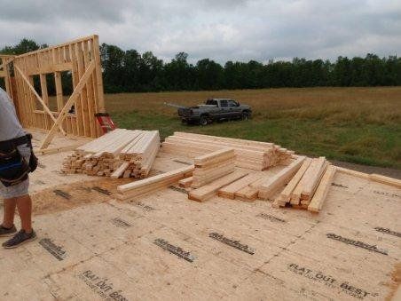 A truck is parked in a field next to a pile of wood.