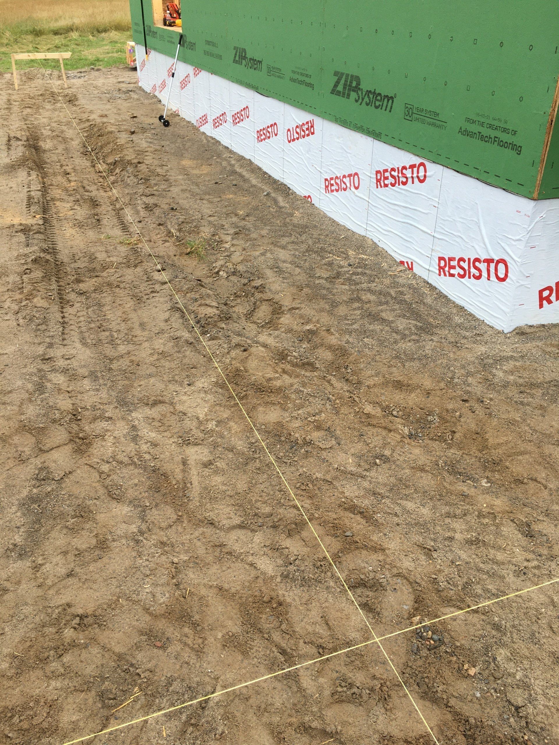 A green building is sitting on top of a dirt field.
