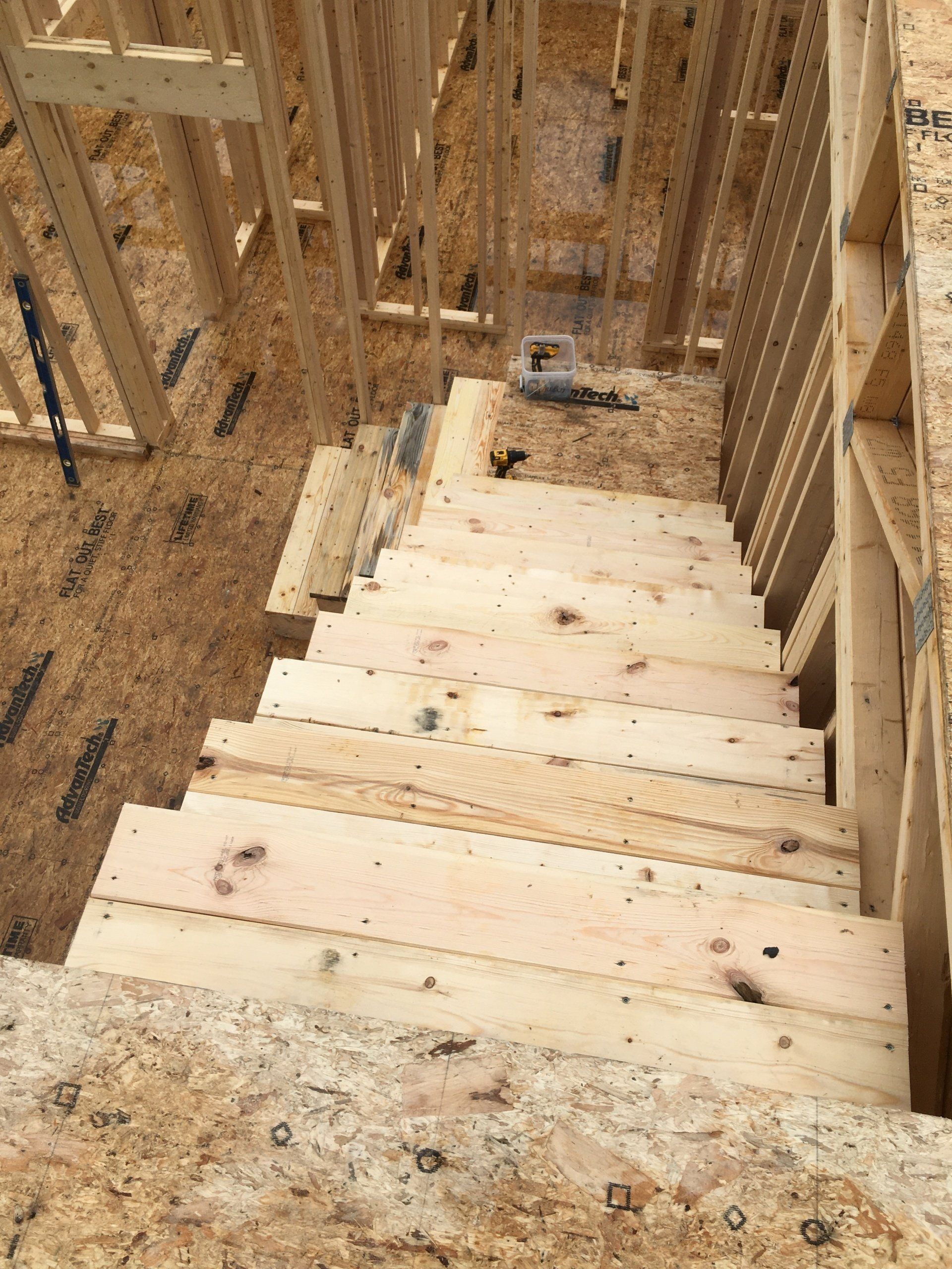 A wooden staircase is being built in a house under construction.