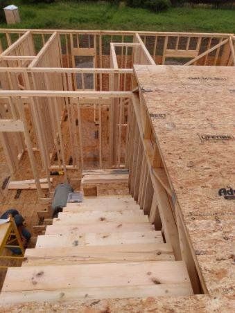 A wooden staircase leading up to the second floor of a house under construction.