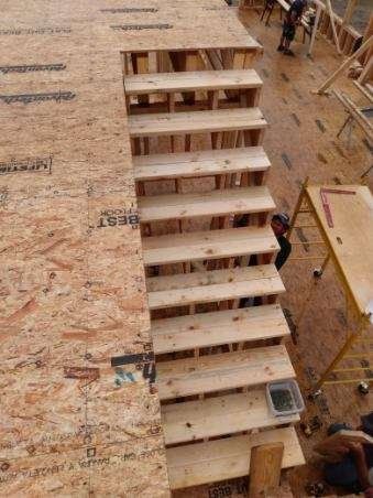 A wooden staircase is being built on top of a wooden floor.