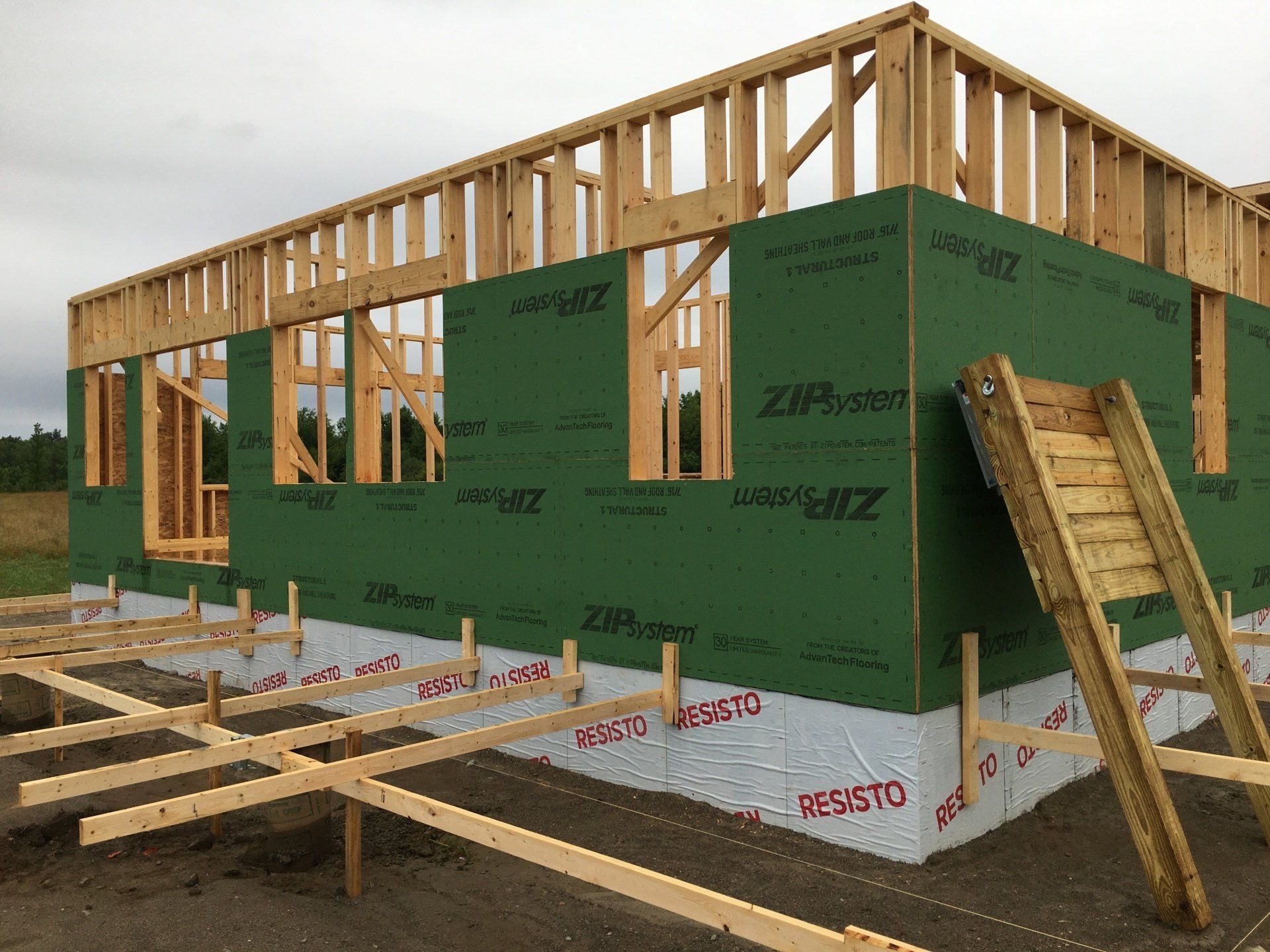 A house is being built with wooden frames and green walls.