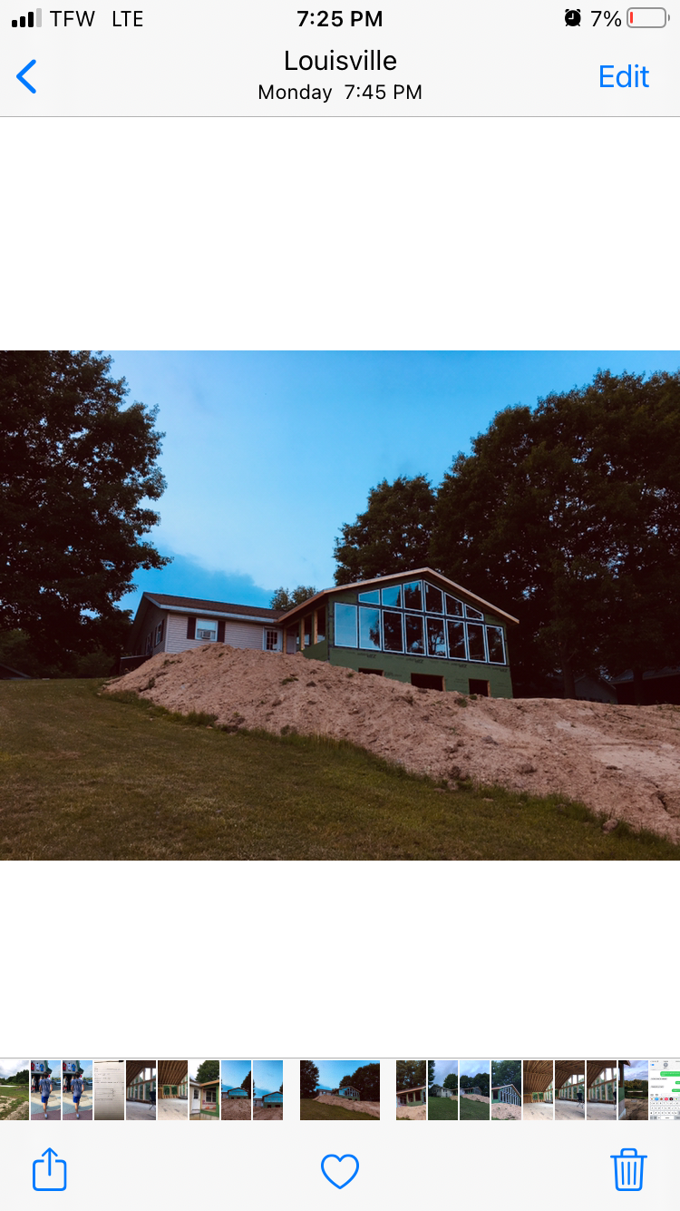 A phone screen shows a picture of a house under construction.