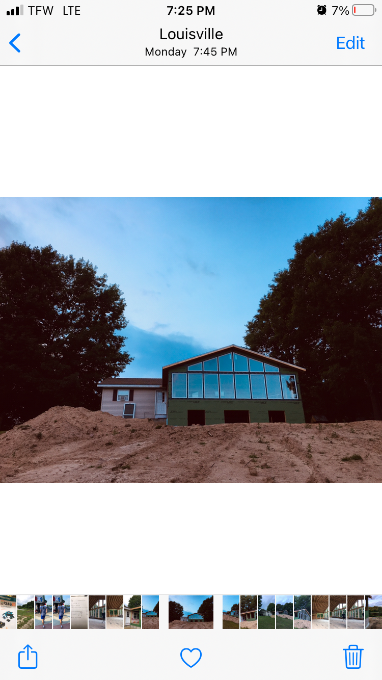 A phone screen shows a picture of a house under construction.