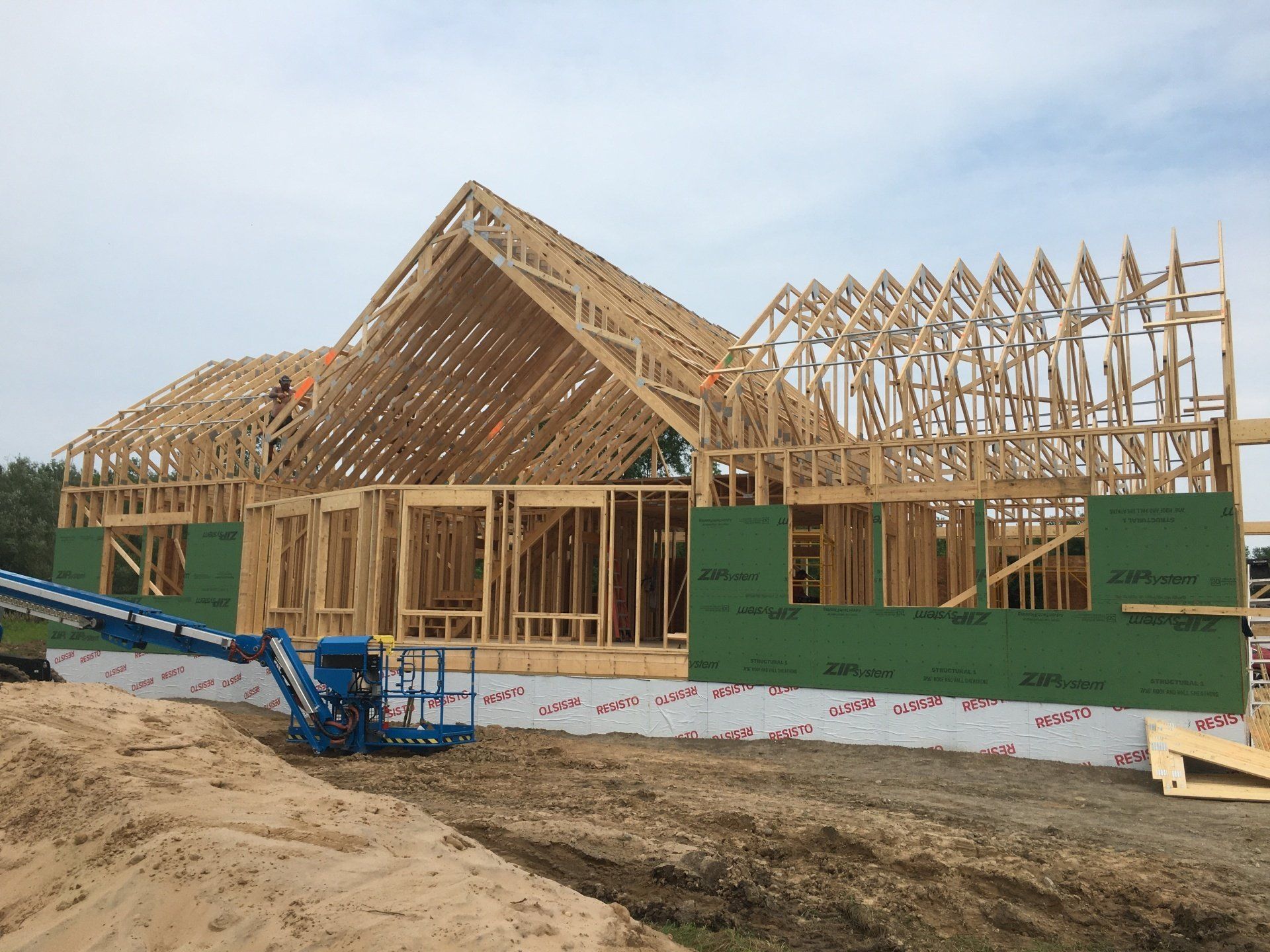 A large wooden house is being built on a dirt field.