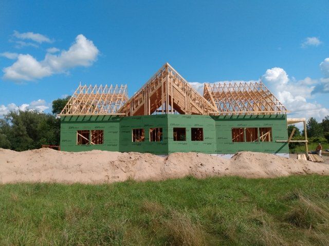A house is being built in a field with a blue sky in the background.