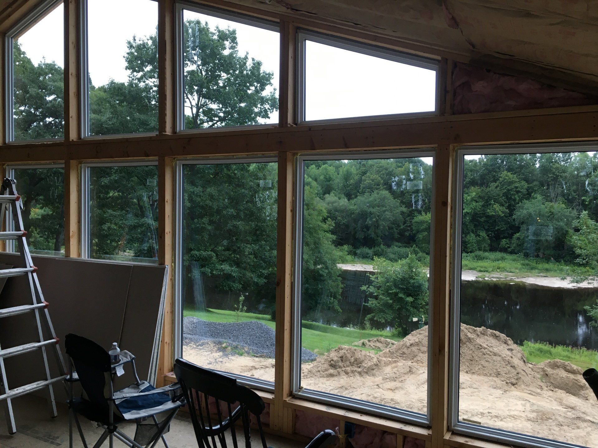 A room with a lot of windows looking out to a river