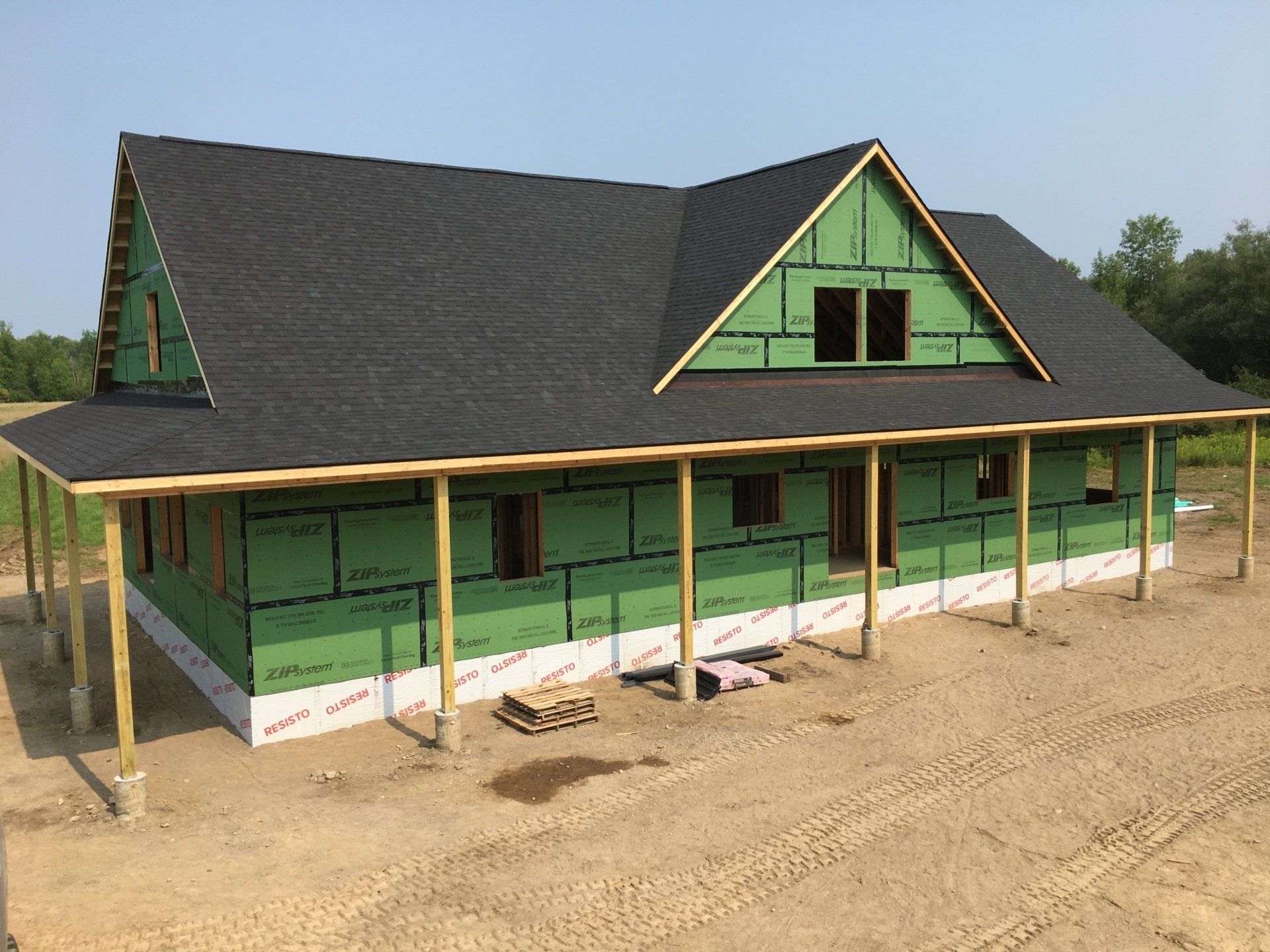 A house is being built with a black roof and green siding.