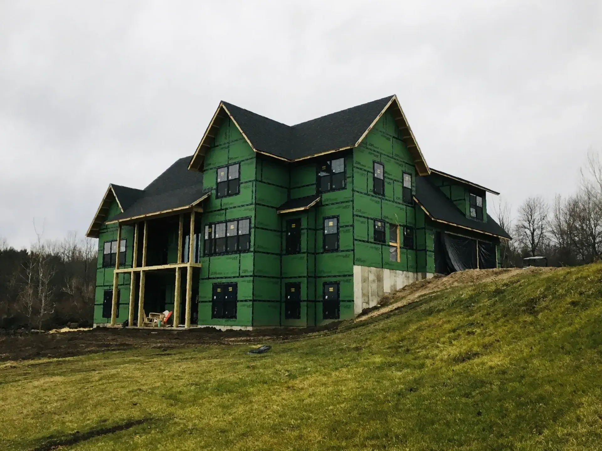 A large house is being built on top of a grassy hill.