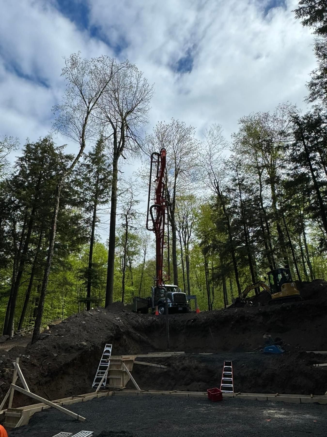 A construction site with a crane in the middle of the woods
