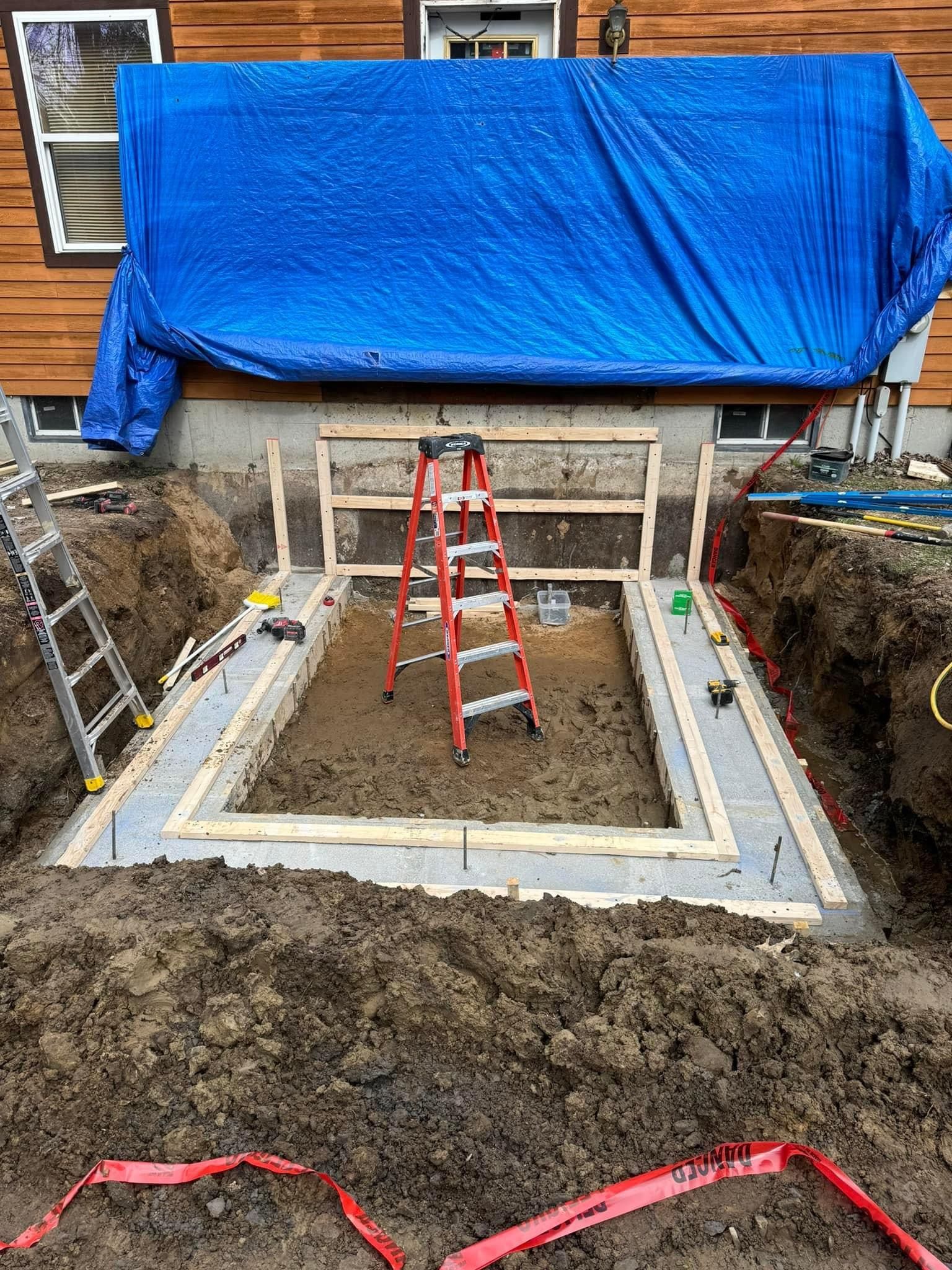 A blue tarp is covering a hole in the ground next to a ladder.