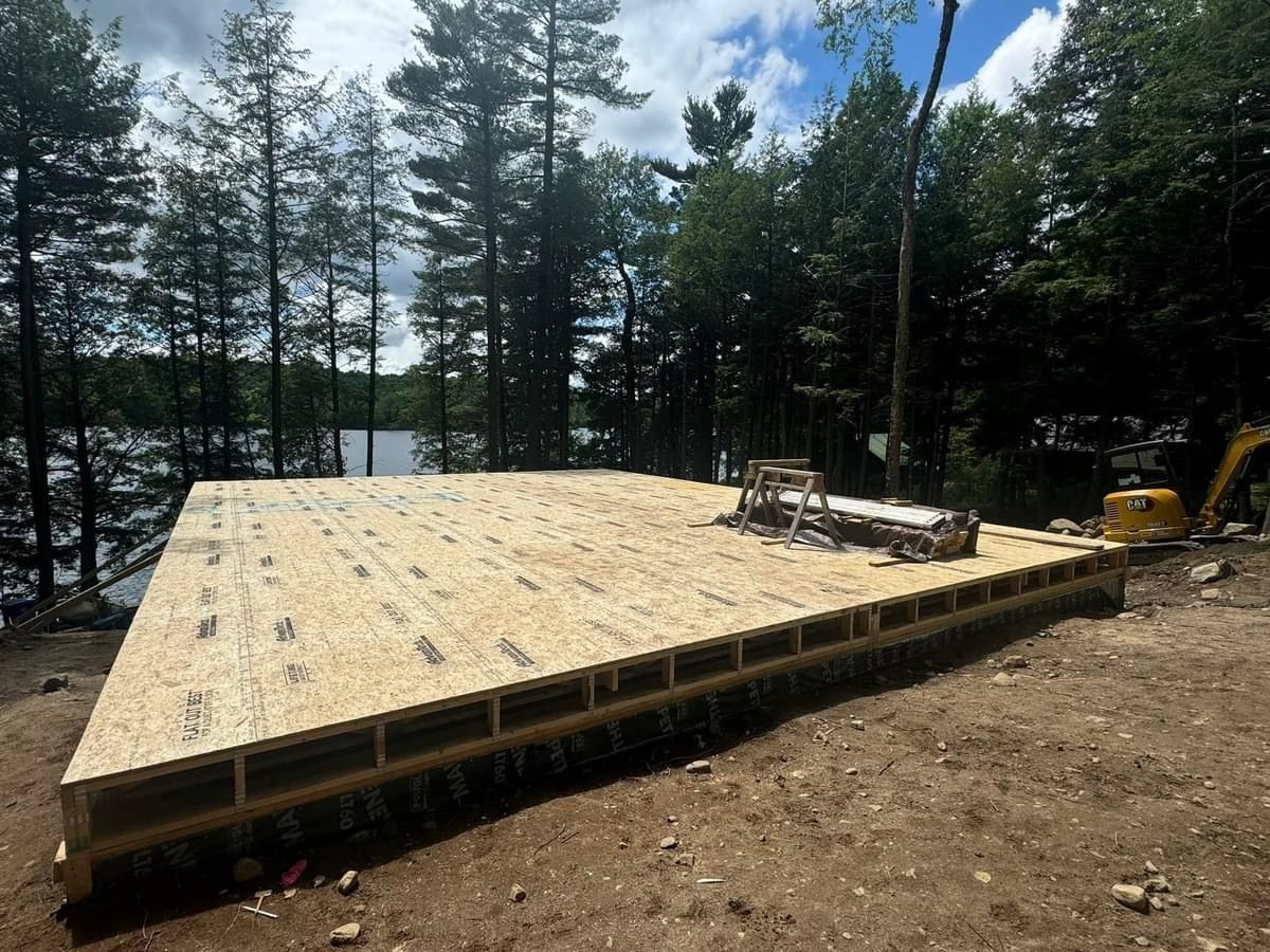A large wooden platform is being built in the middle of a forest.
