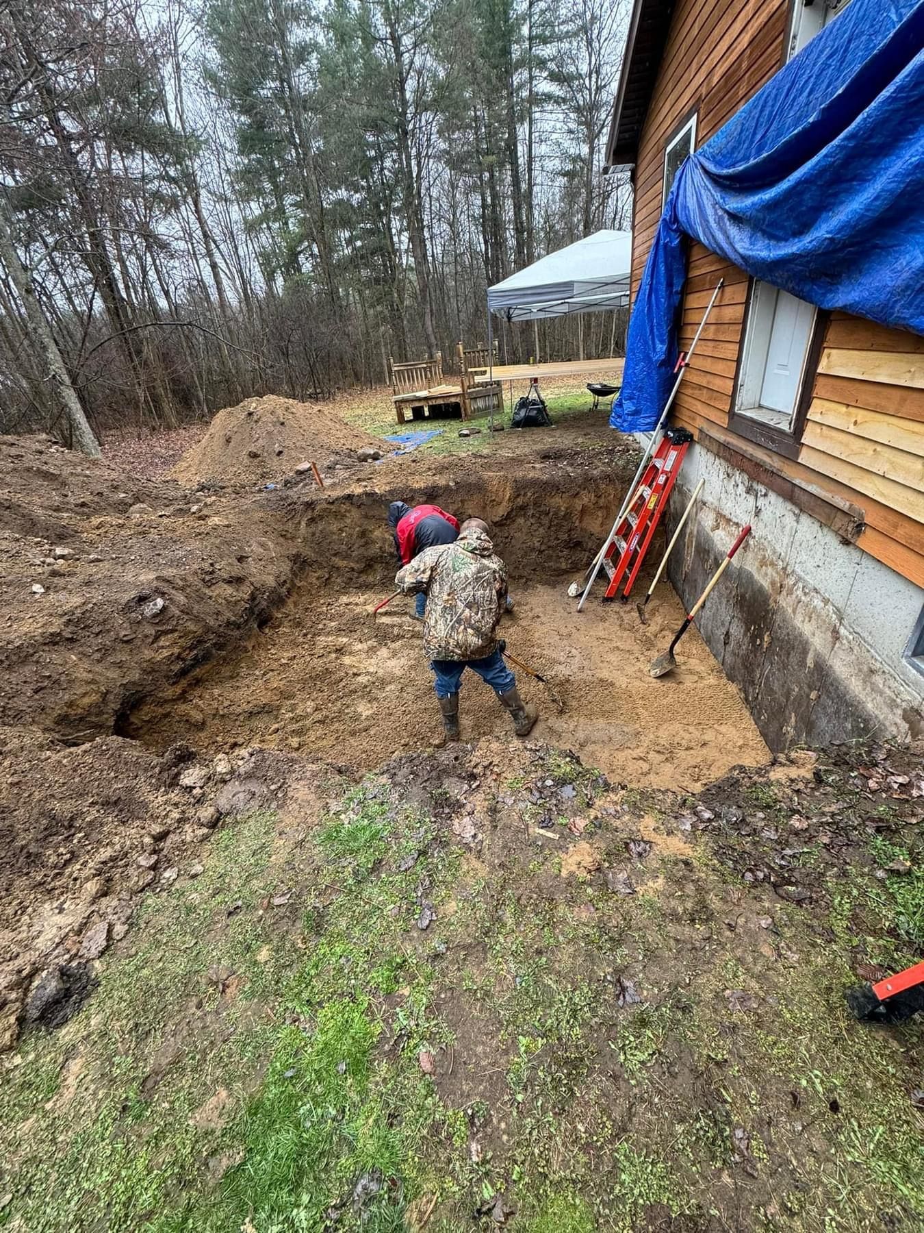 A little boy is digging a hole in the dirt in front of a house.