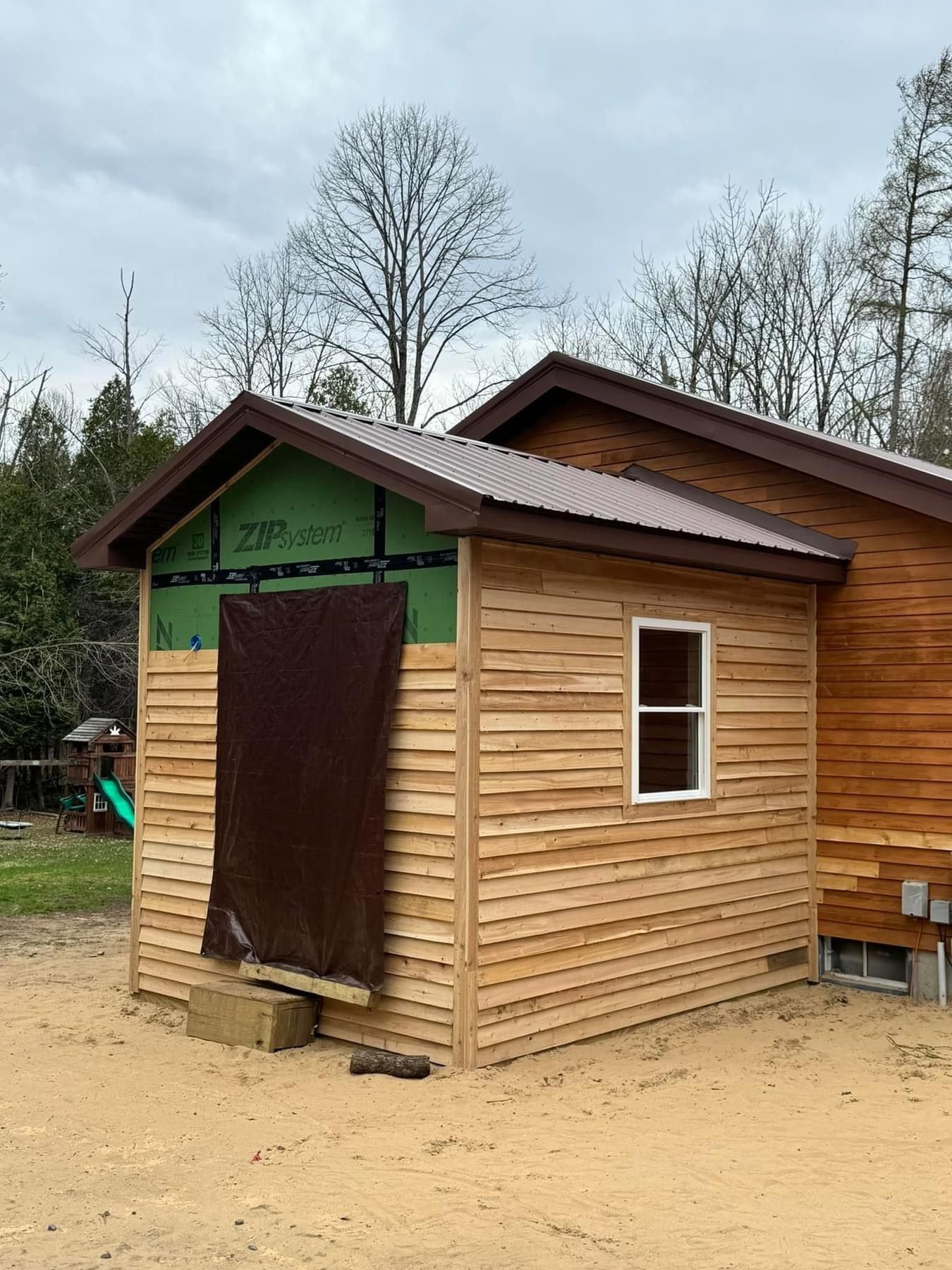 A small wooden shed with a window and a roof is being built.