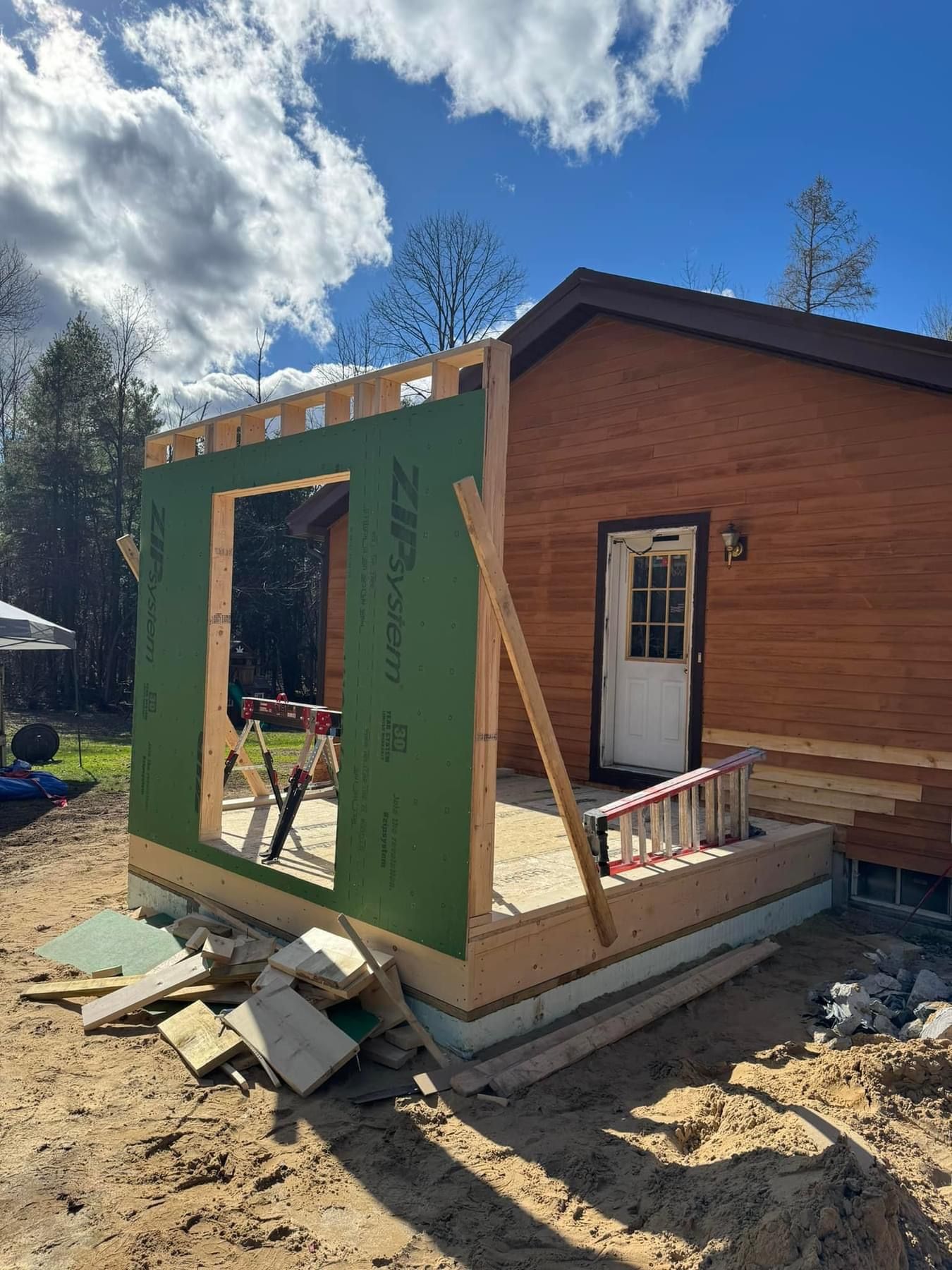 A wooden house is being built with a green wall and a white door.