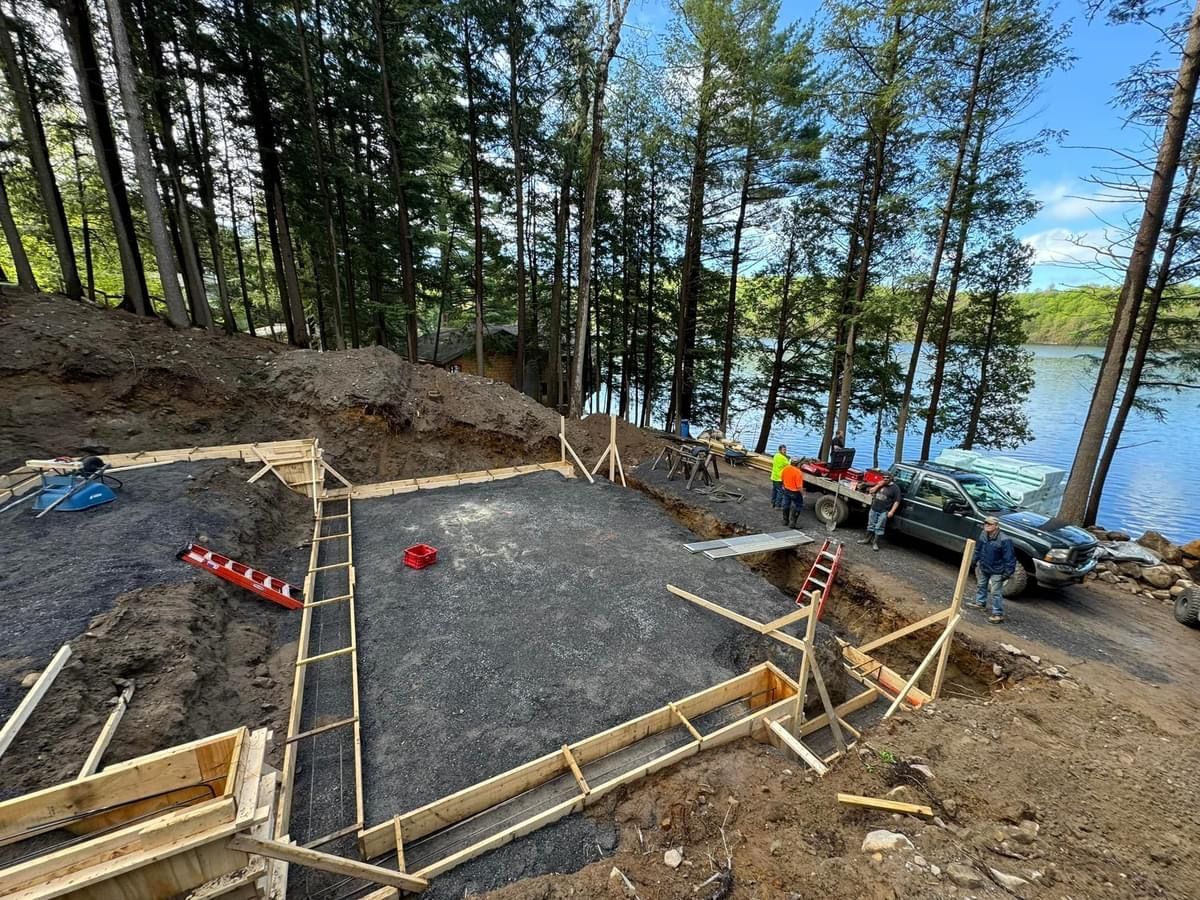 A building is being built next to a lake in the woods.